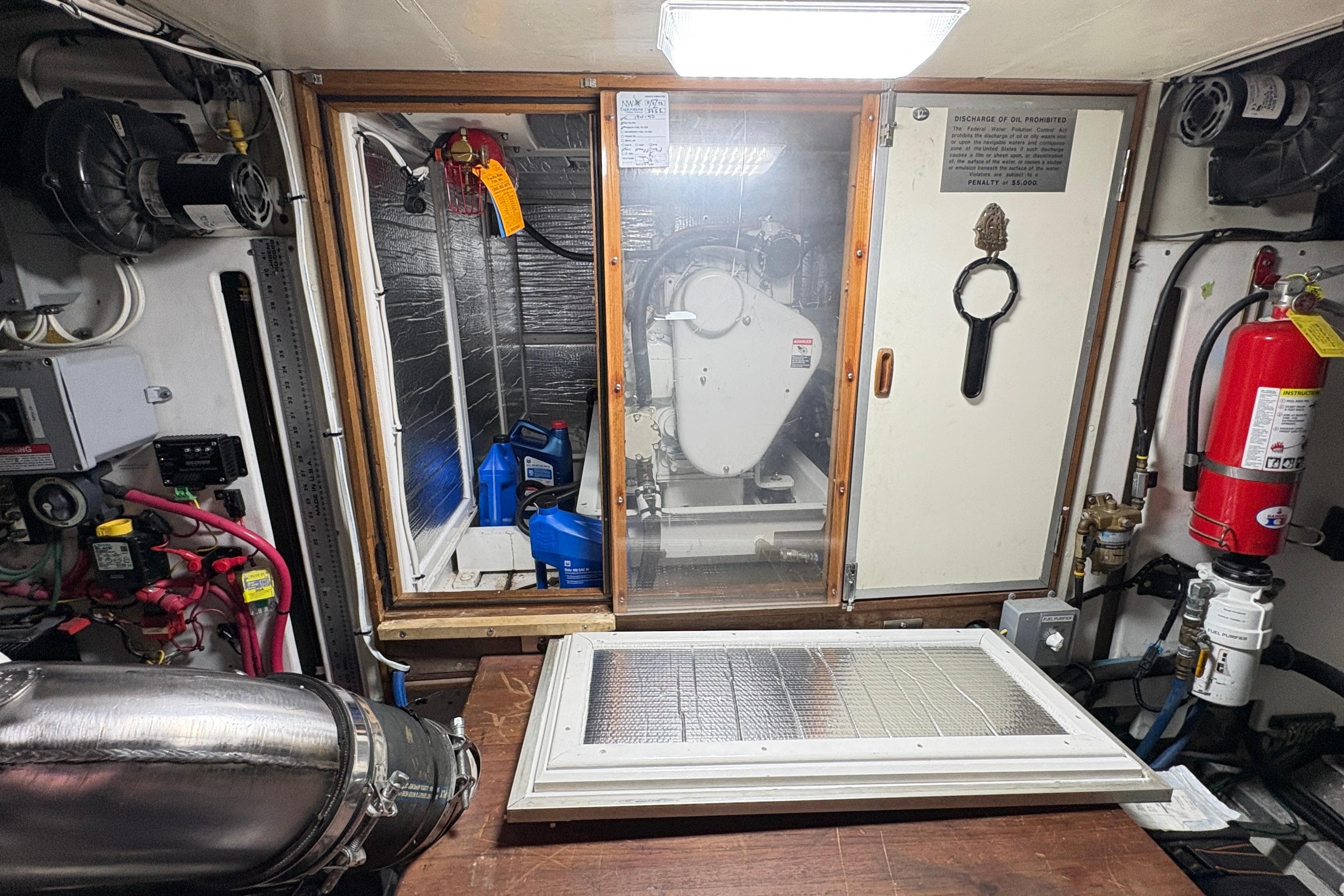 Engine room of 1984 Grand Banks 49 Classic yacht with equipment and fire extinguisher.