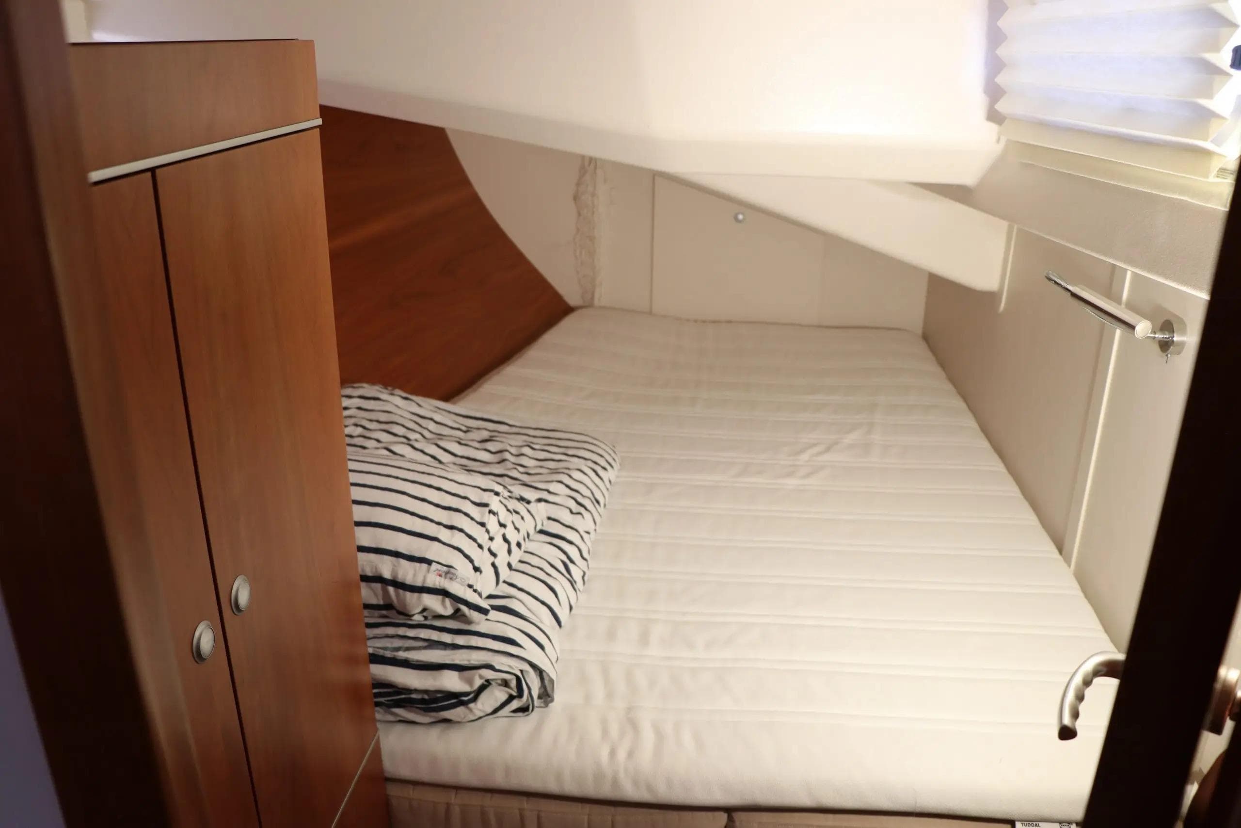 Cozy cabin interior of 2011 Hanse 445 yacht with striped bedding.