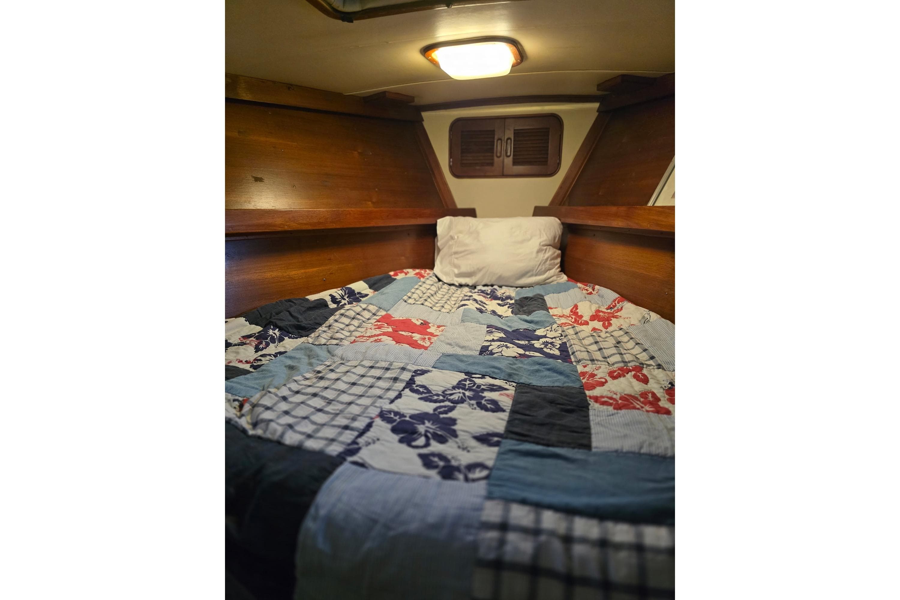 Cozy cabin bed with colorful quilt in 1982 Irwin 52 sailboat.