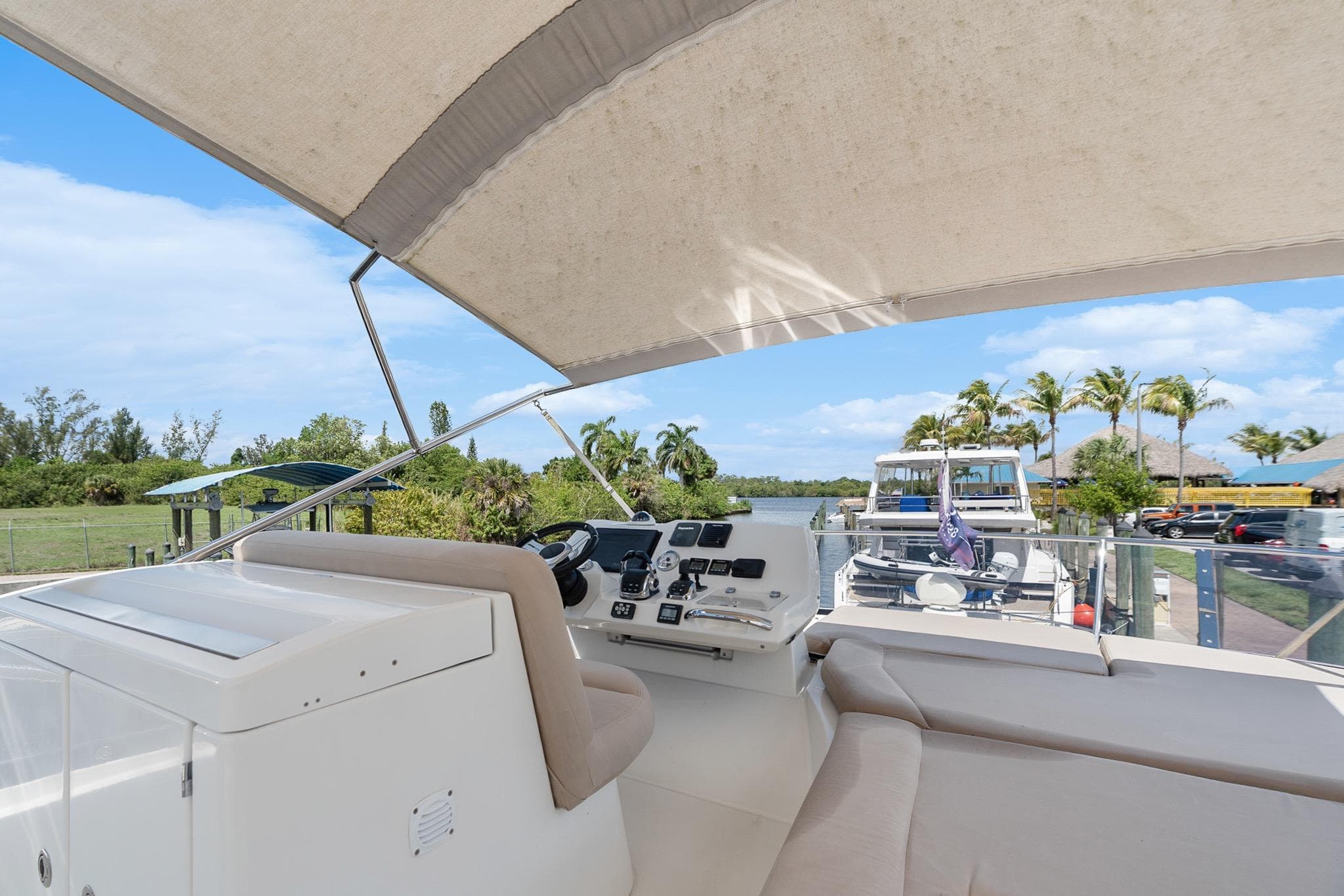 Flybridge of 2016 Prestige 500 yacht with helm, seating, and canopy in marina setting.