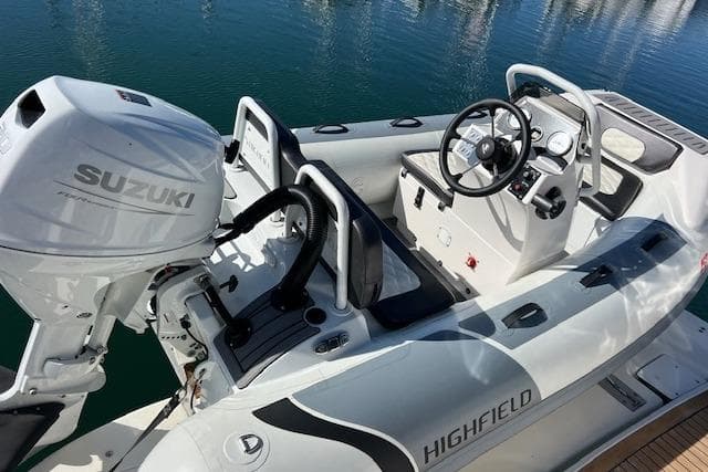Highfield boat with Suzuki outboard motor, docked on calm water. Sea Ray 450 Sundancer, 1997.
