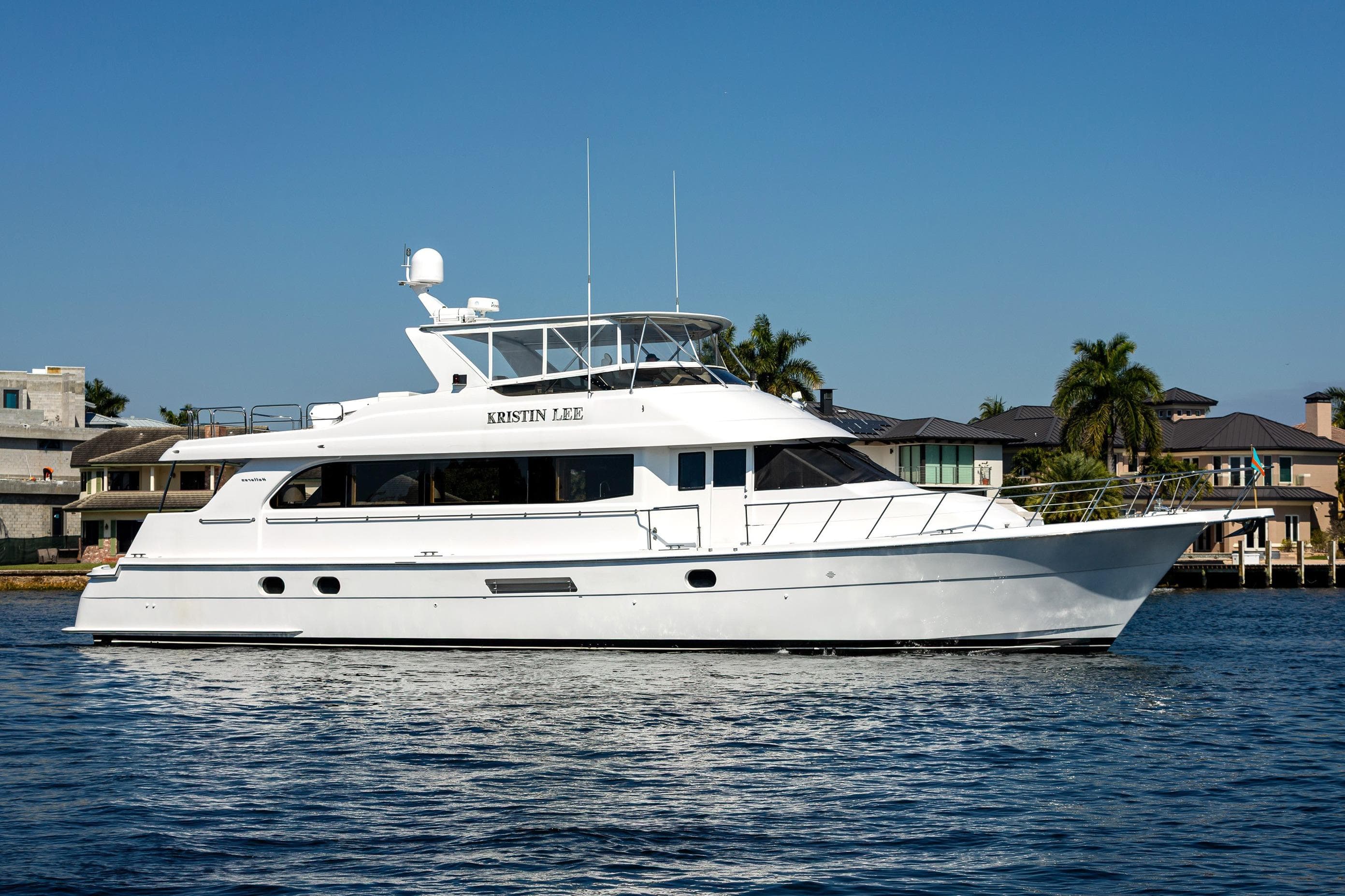 2001 Hatteras 75 Cockpit Motor Yacht on calm water, with luxury homes in the background.