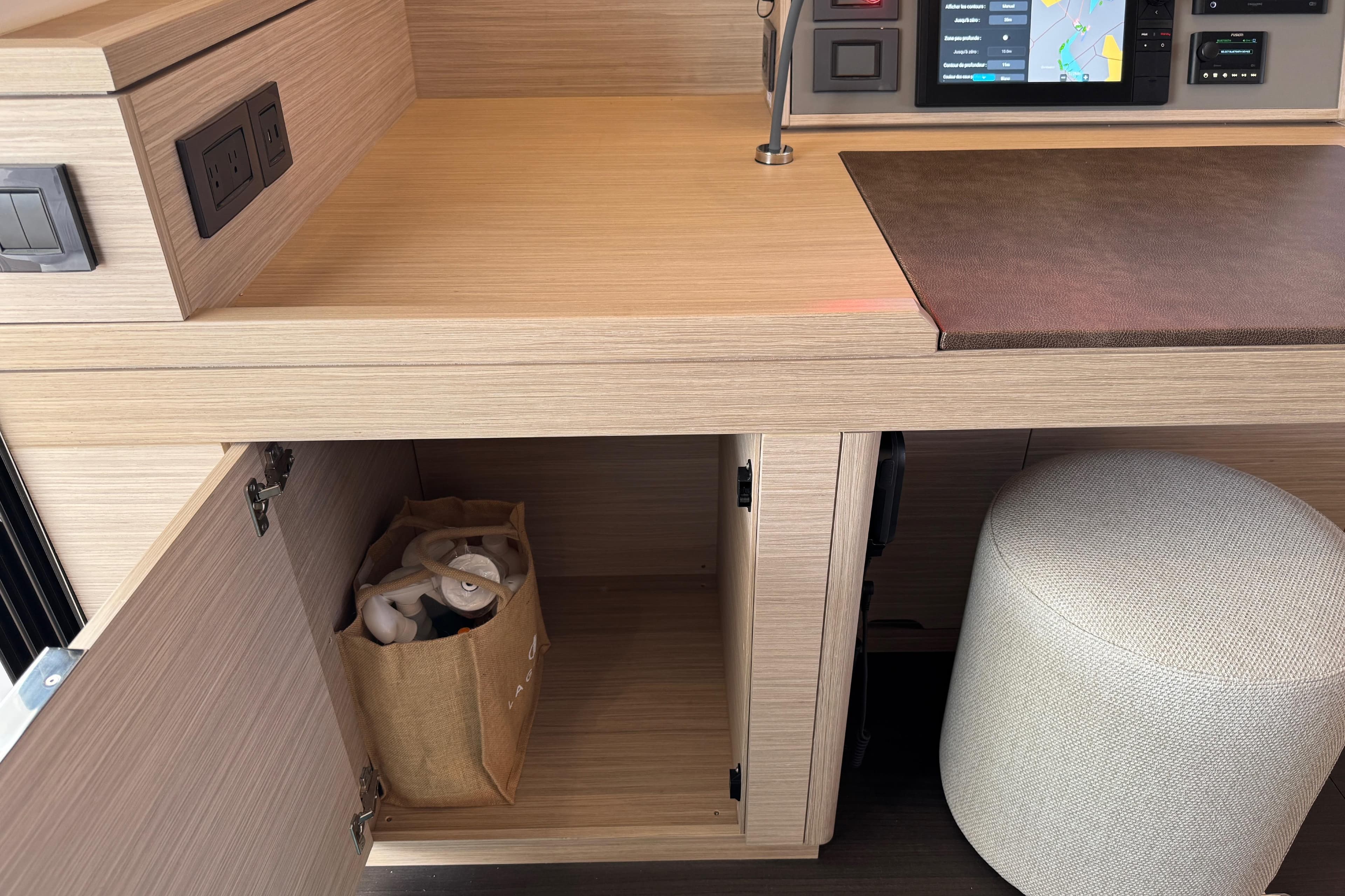 Modern interior of 2026 Lagoon 55 yacht with open cabinet and control panel.