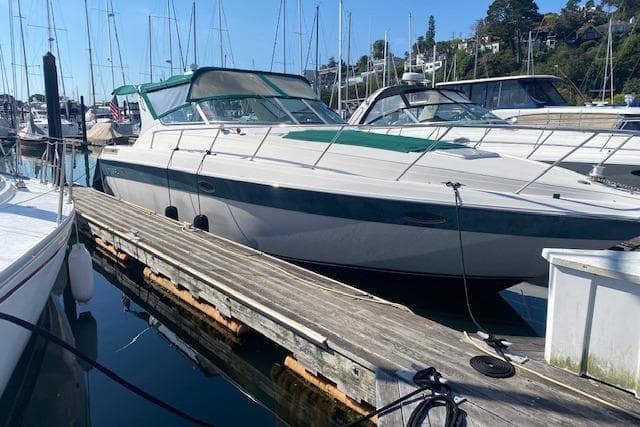 1995 Regal 402 boat docked at marina with clear blue sky background.