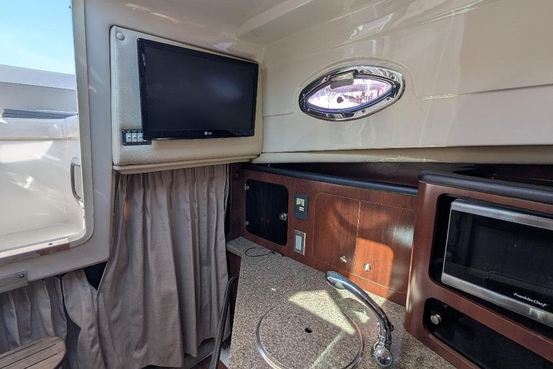 2014 Robalo R305 Walkaround cabin interior with TV, sink, and microwave.