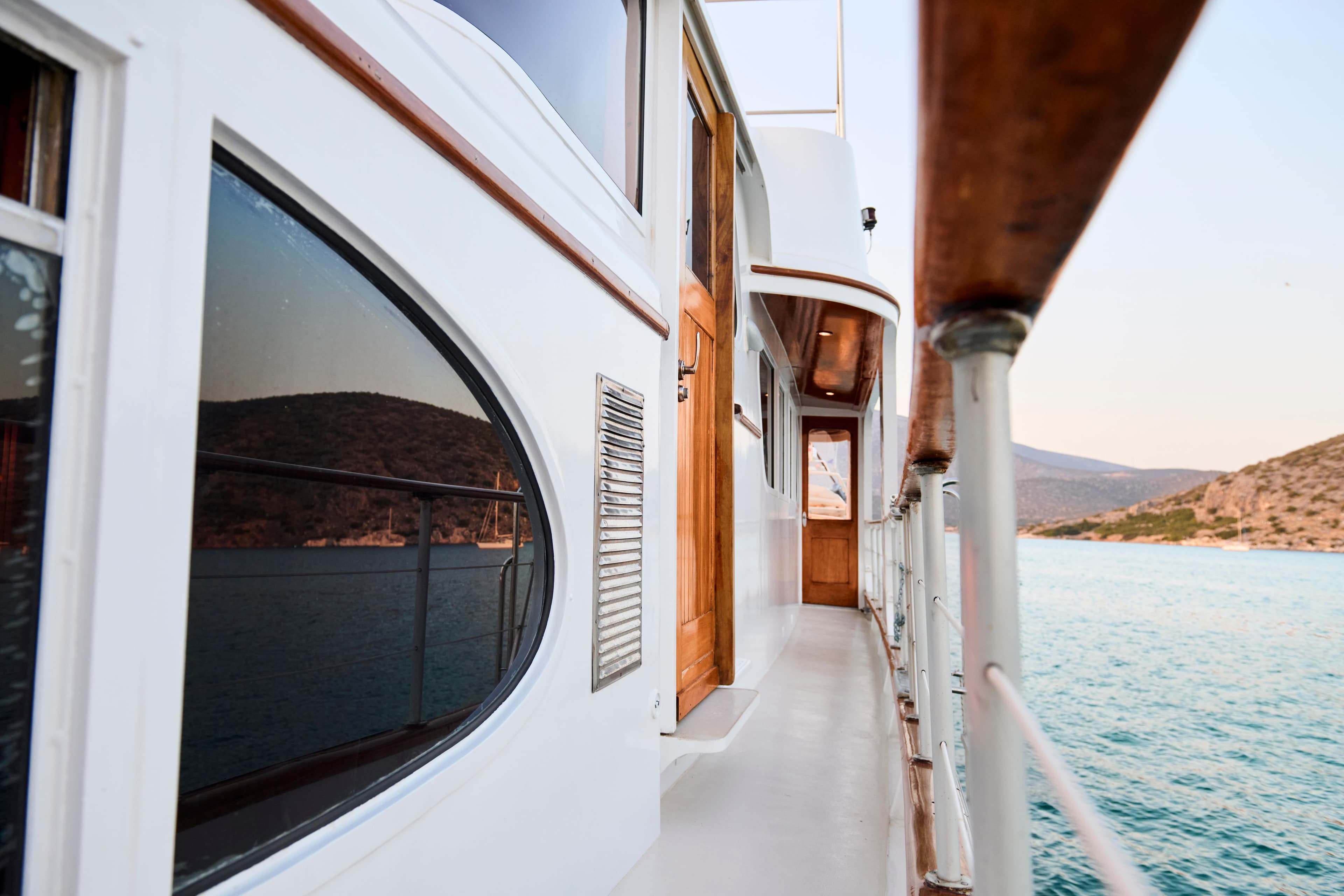 Side view of a 1960 Burger 85 yacht, featuring wooden doors and scenic ocean backdrop.