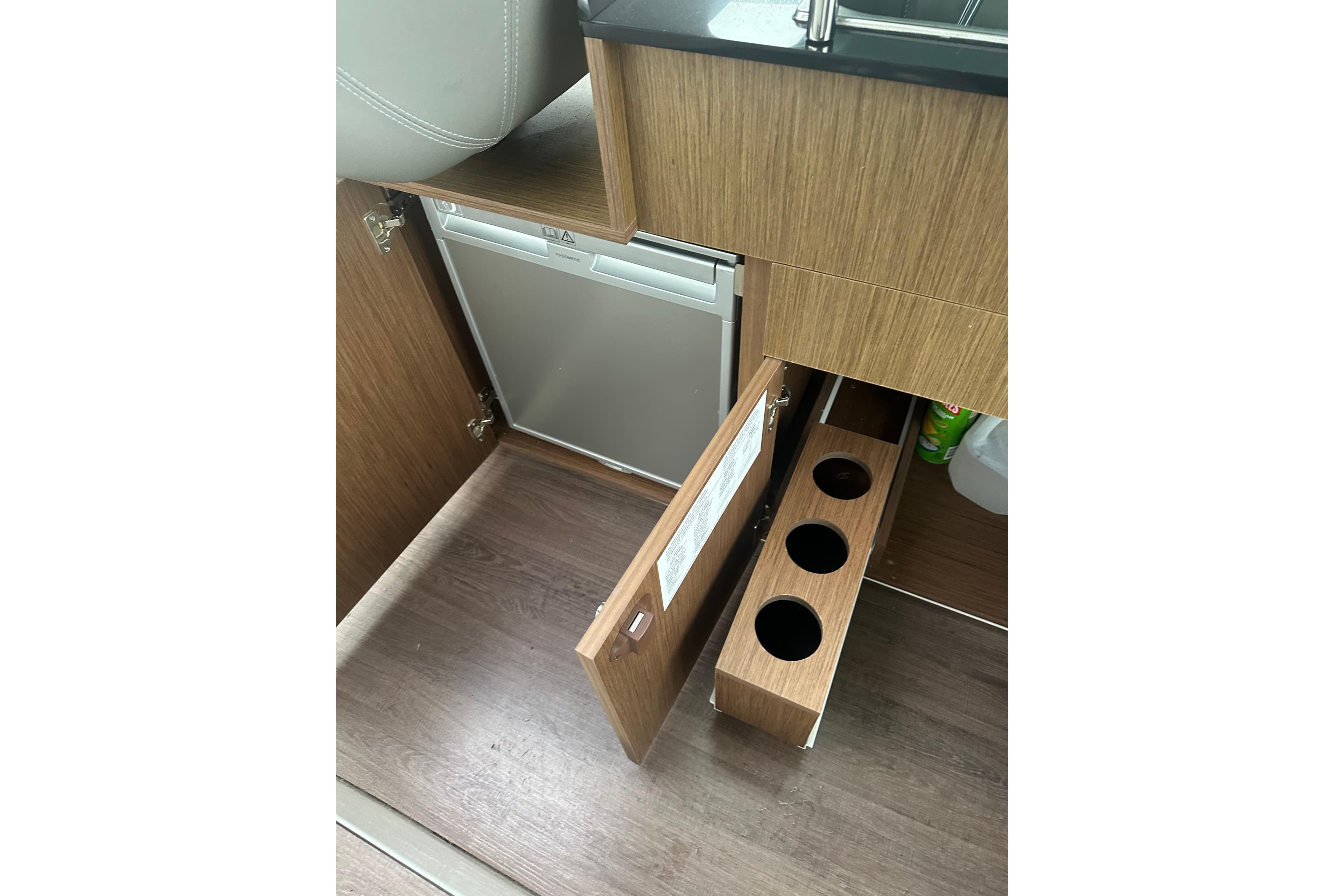 Interior of 2023 Beneteau Antares 9 showing wooden cabinetry and compact refrigerator.