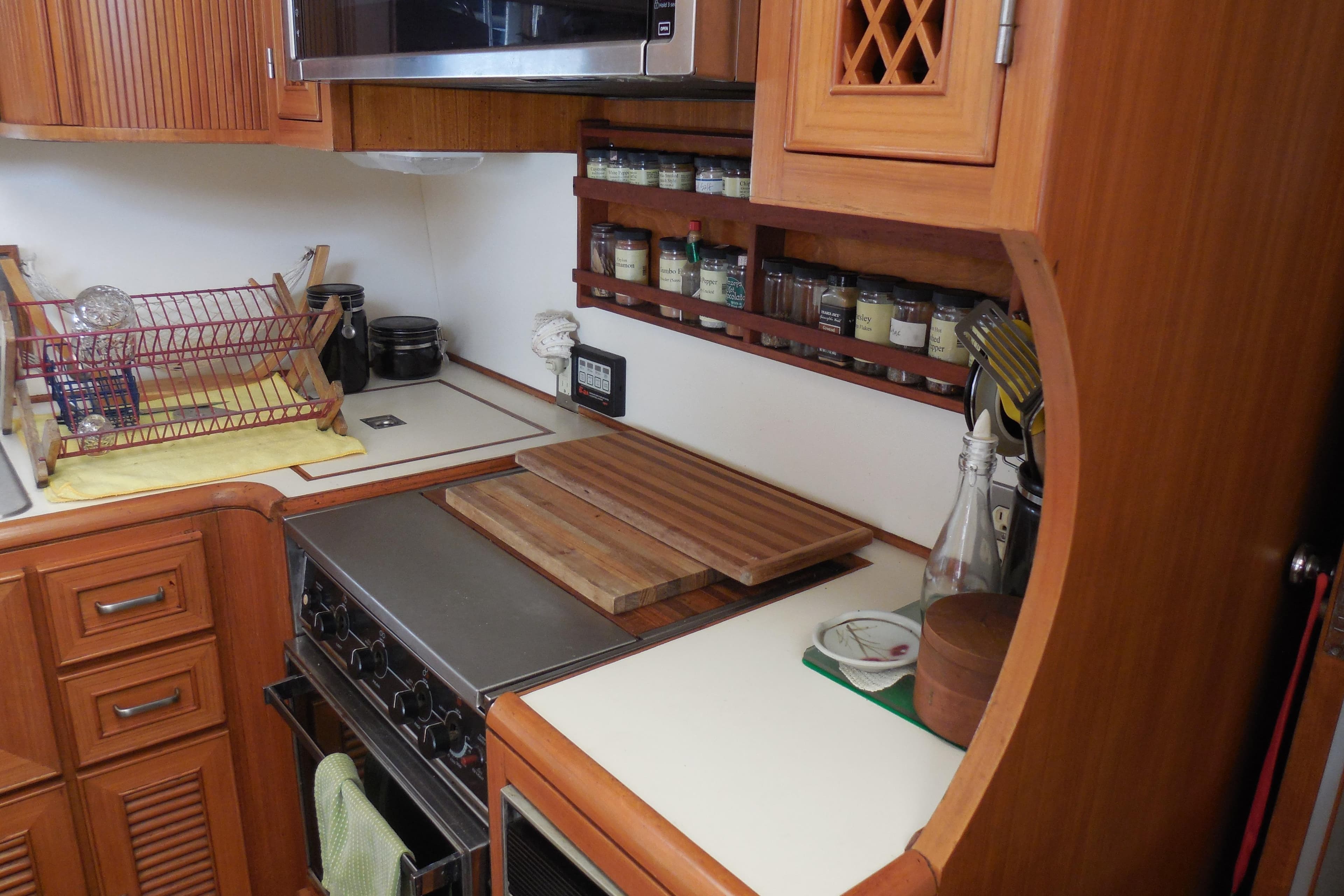 1987 Hi-Star Sundeck yacht kitchen with wooden cabinetry, stove, spice rack, and dish rack.