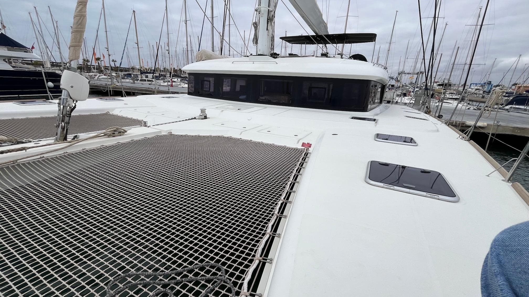 2015 Lagoon 620 catamaran with spacious deck and netting, docked in a marina.