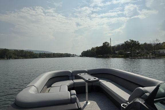 Bennington M Quad Bench 24 MFB 2026 pontoon boat on a serene lake under a cloudy sky.