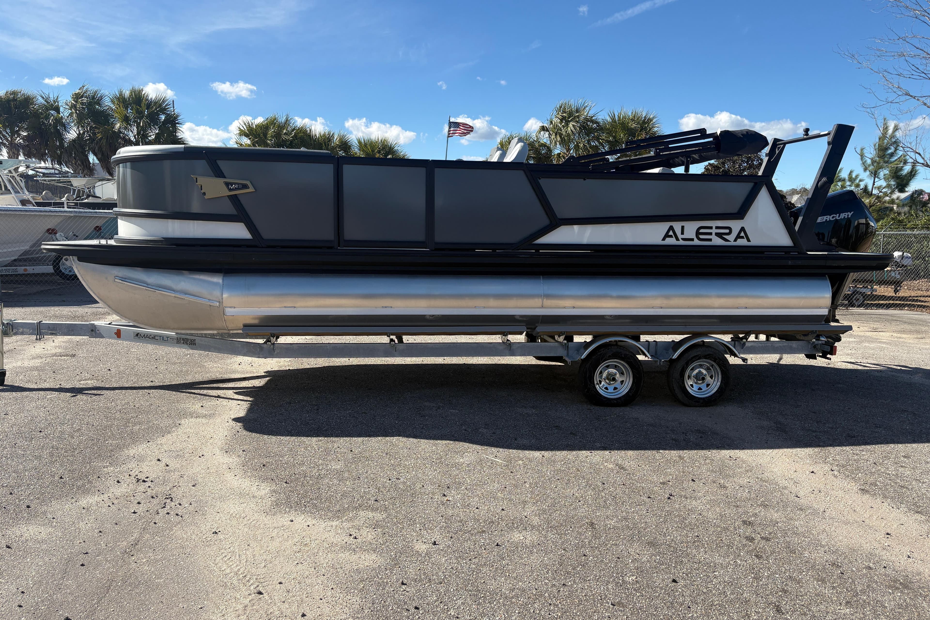 2026 Alera M 23L pontoon boat on trailer, parked outdoors under clear sky.