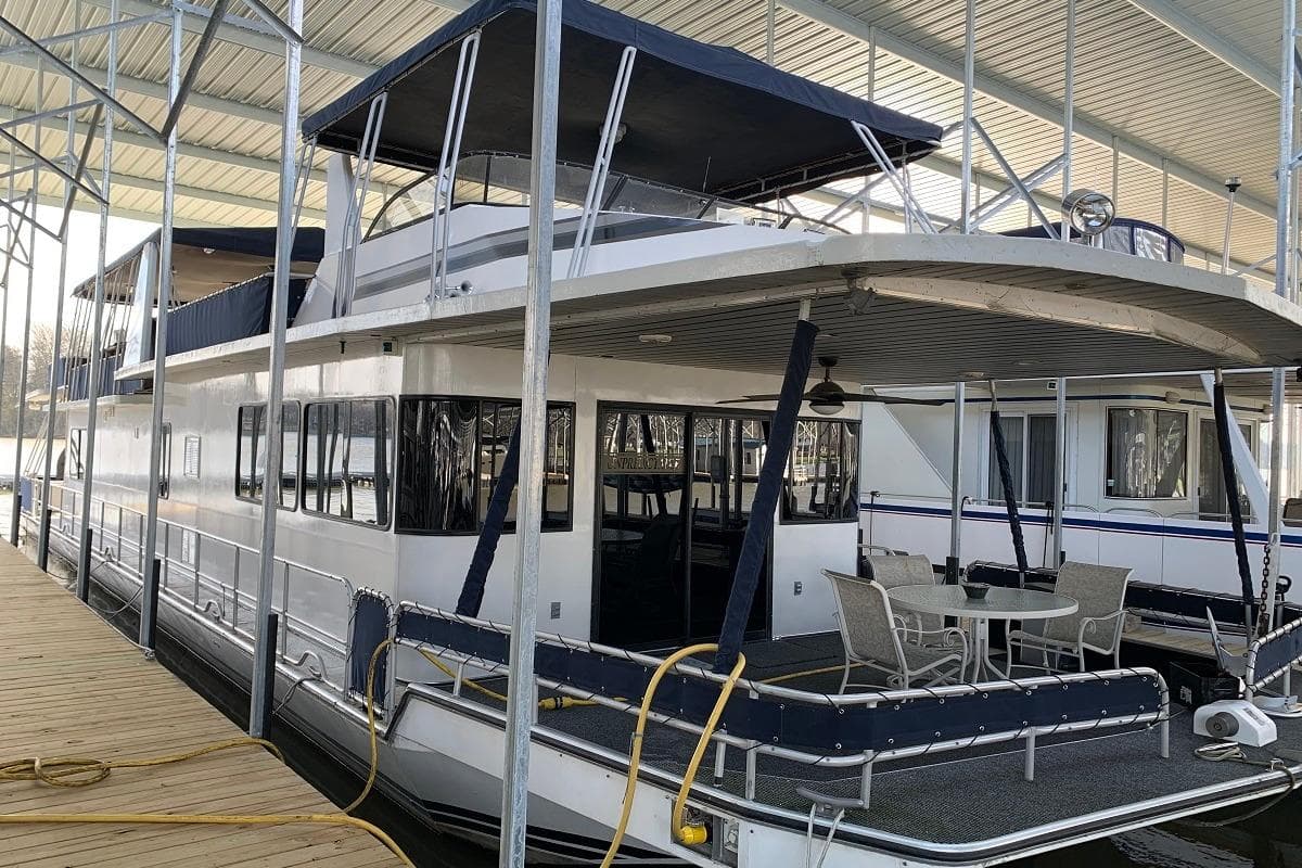 1985 Sumerset 18x81 houseboat docked, featuring spacious deck and covered seating area.
