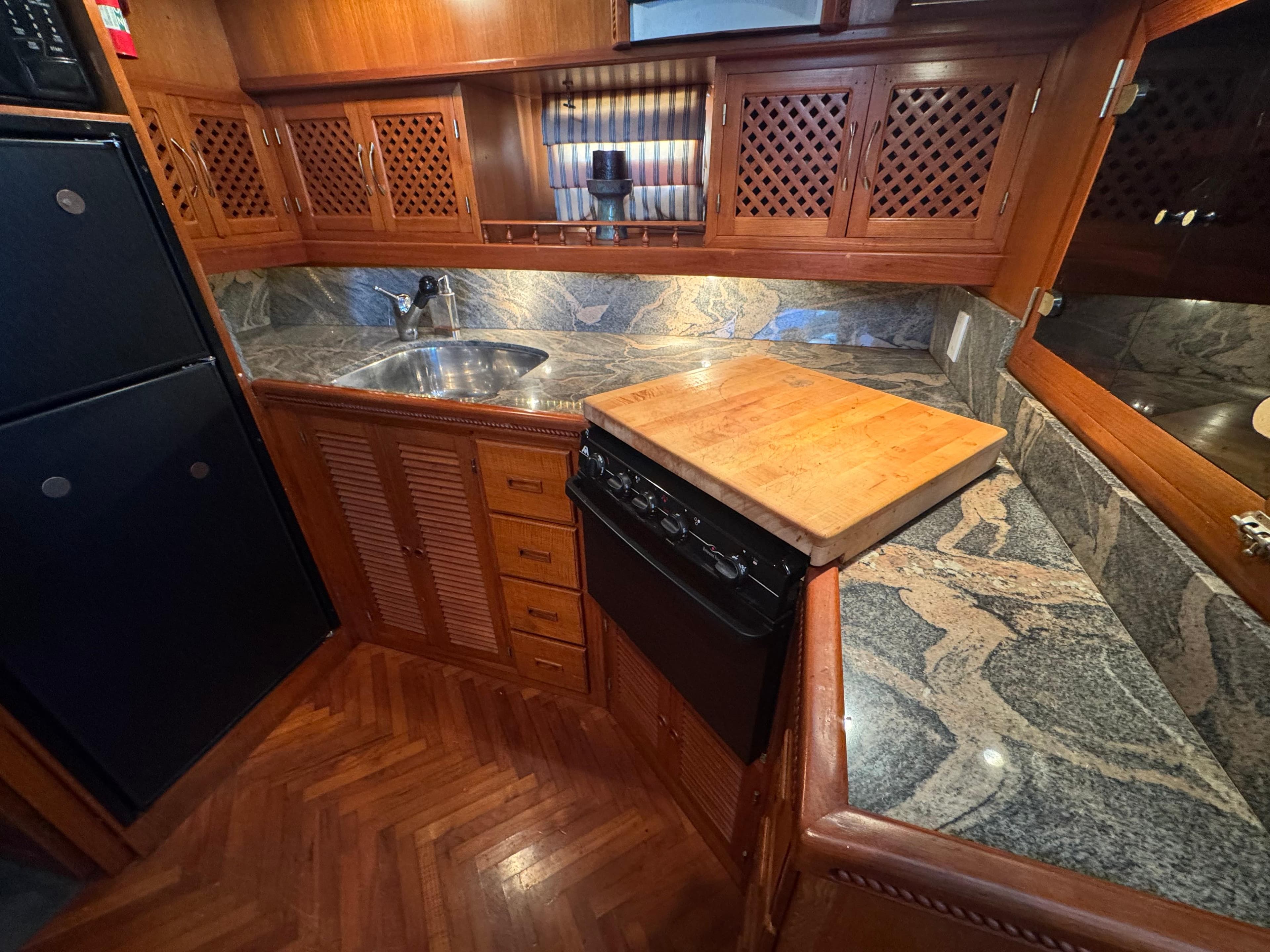 Compact kitchen in a 1990 Nova 48 boat with wood cabinets and granite countertops.