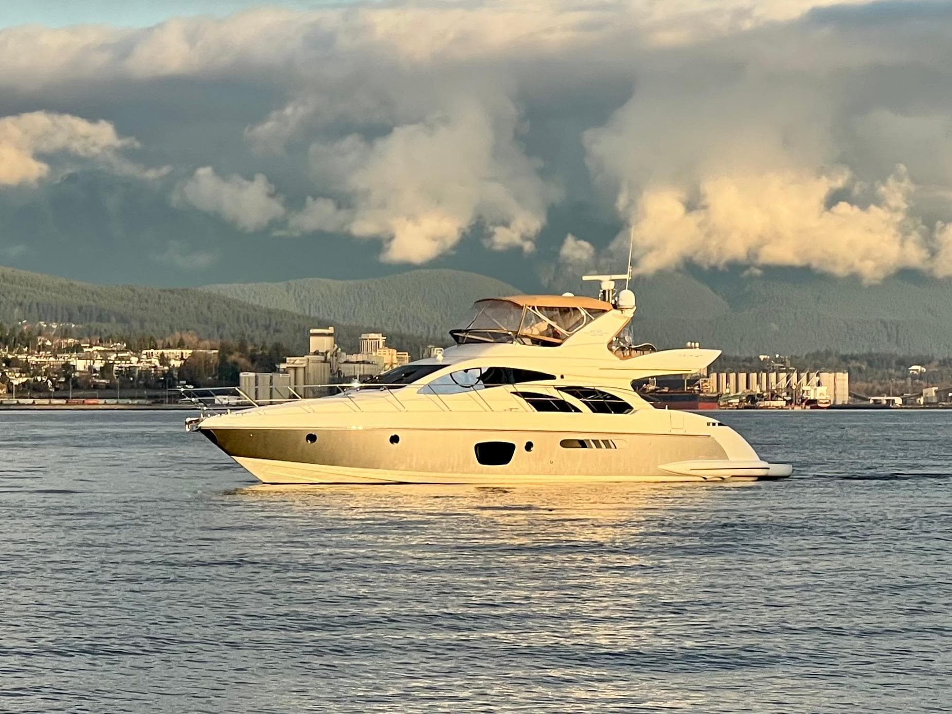 Luxurious 2011 Azimut 55E yacht cruising on calm waters with scenic mountain backdrop.