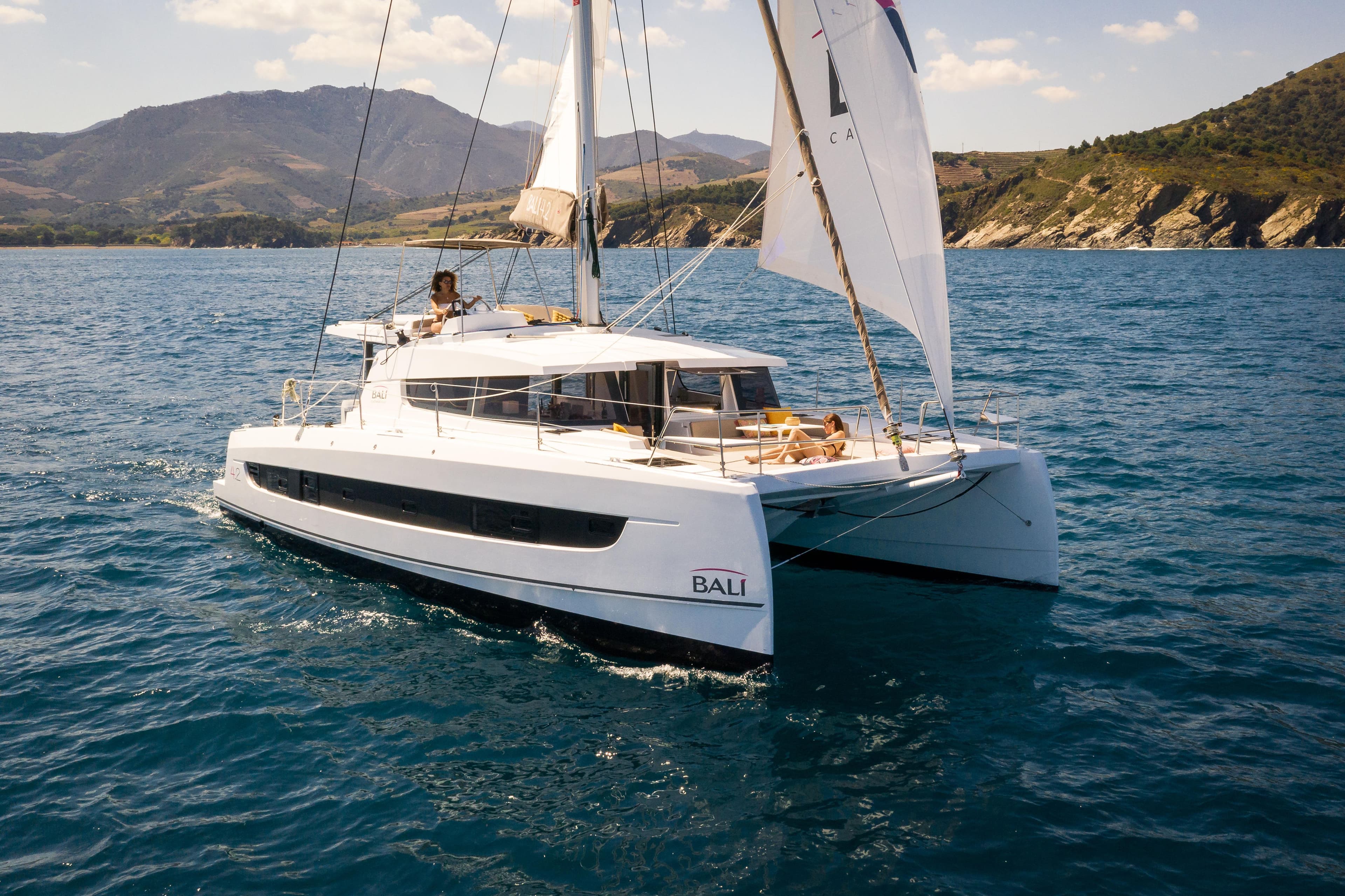 2026 Bali 4.2 catamaran sailing on blue ocean near scenic coastline.