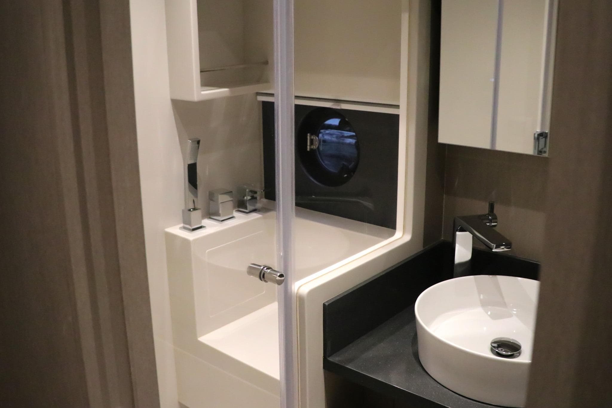Modern bathroom in 2026 Sirena 48 Flybridge yacht with sleek fixtures and porthole window.