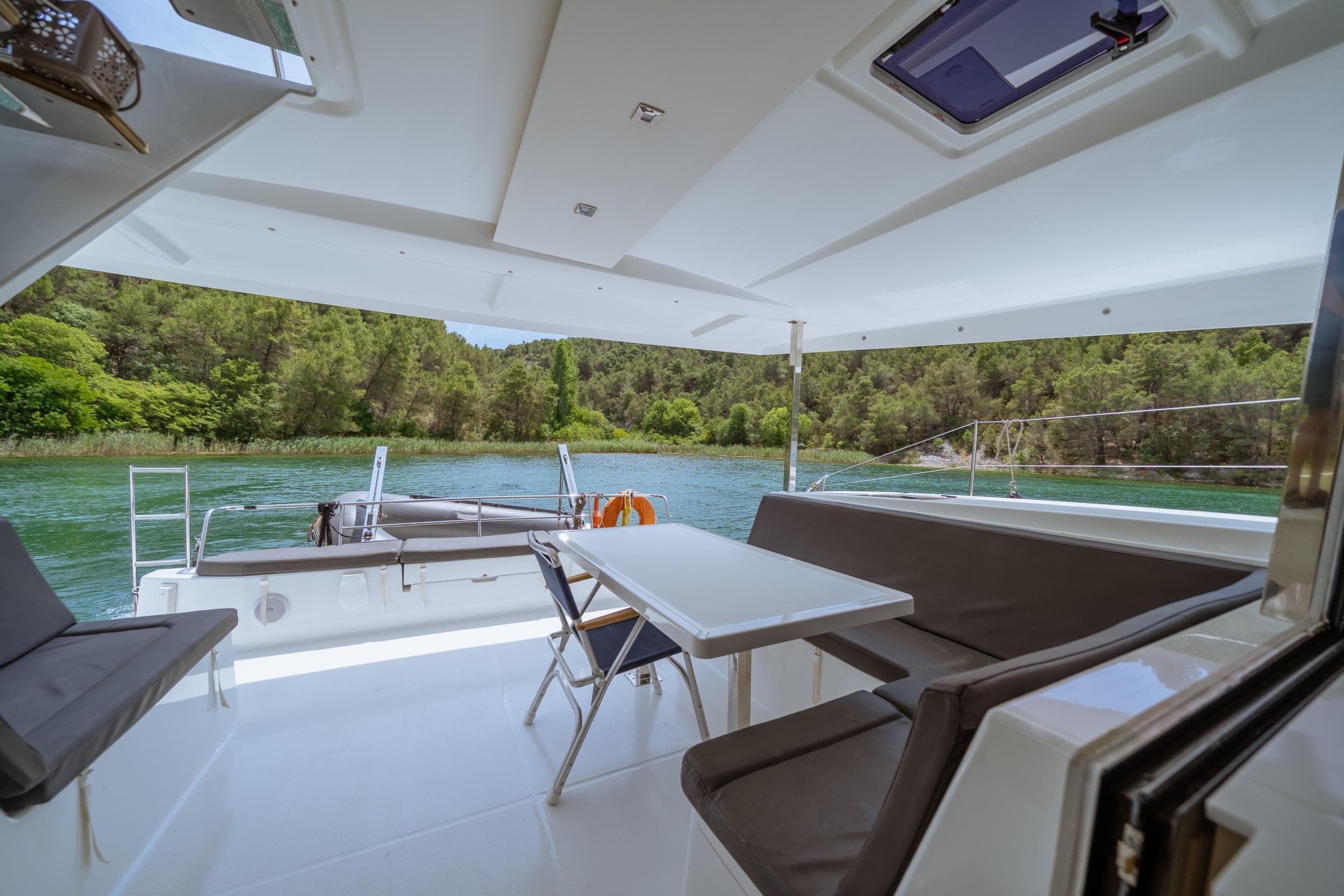 Spacious deck of 2024 Fountaine Pajot Isla 40 catamaran with scenic river view.