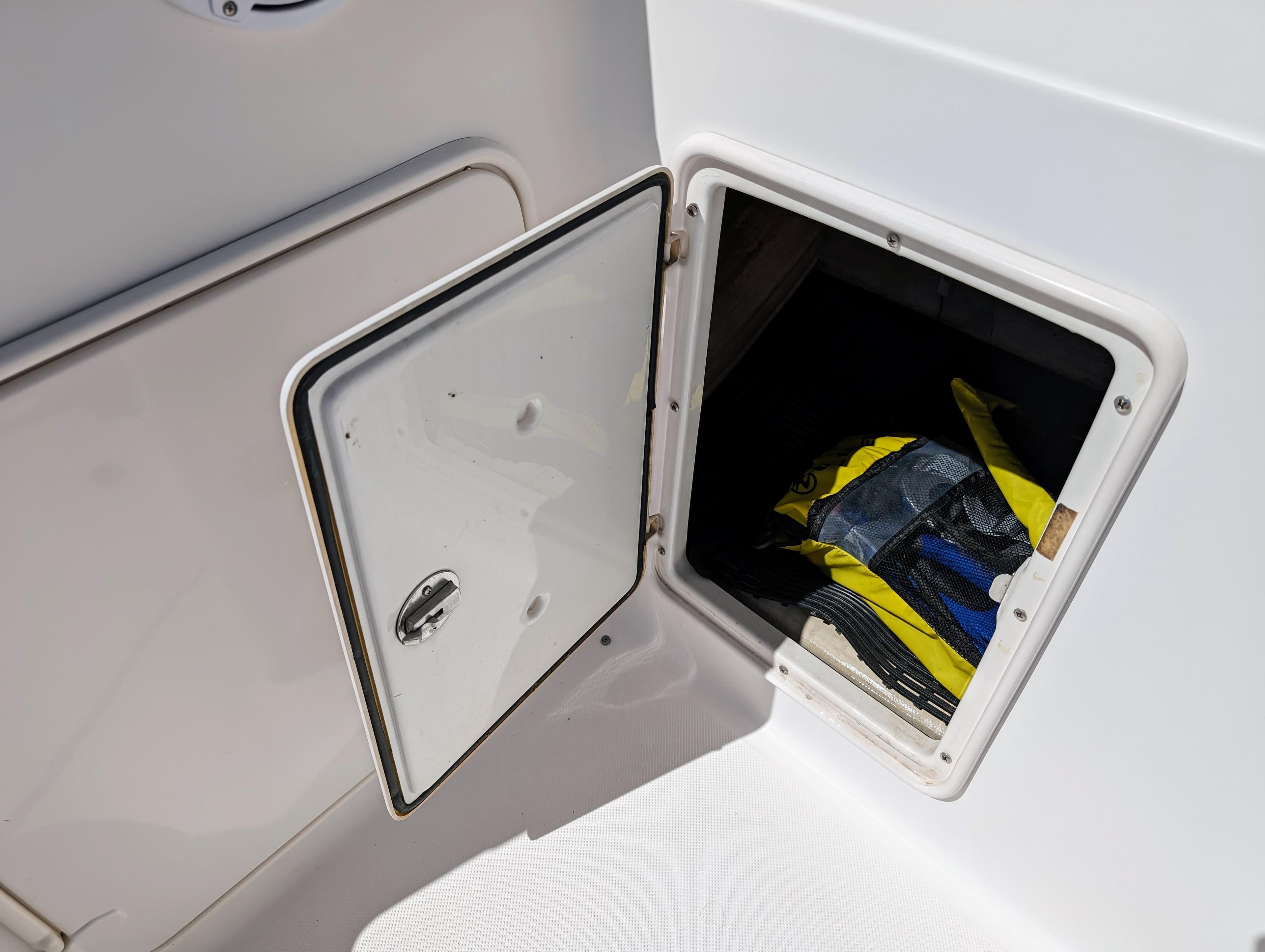 Open storage compartment on 2005 Regal 3560 boat with gear inside.