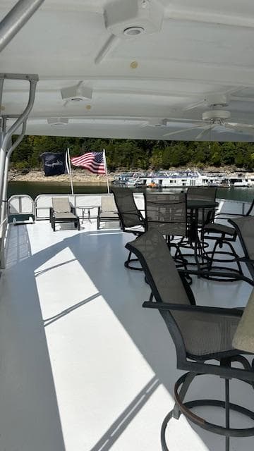 2007 Sharpe 18 x 85 Houseboat deck with chairs, tables, and American flag.