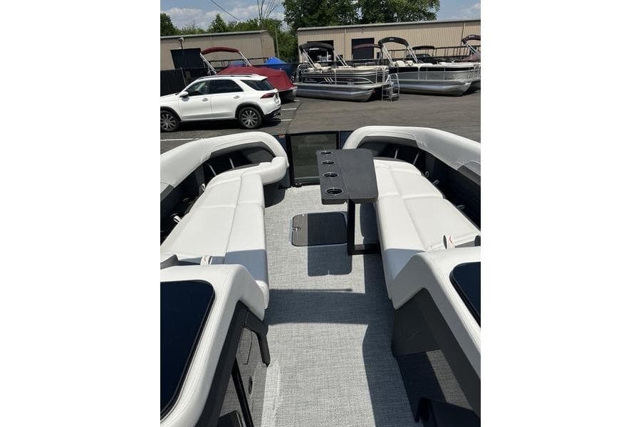 2026 Flamingo Rove 24' boat interior with white seating and central table, parked outdoors.