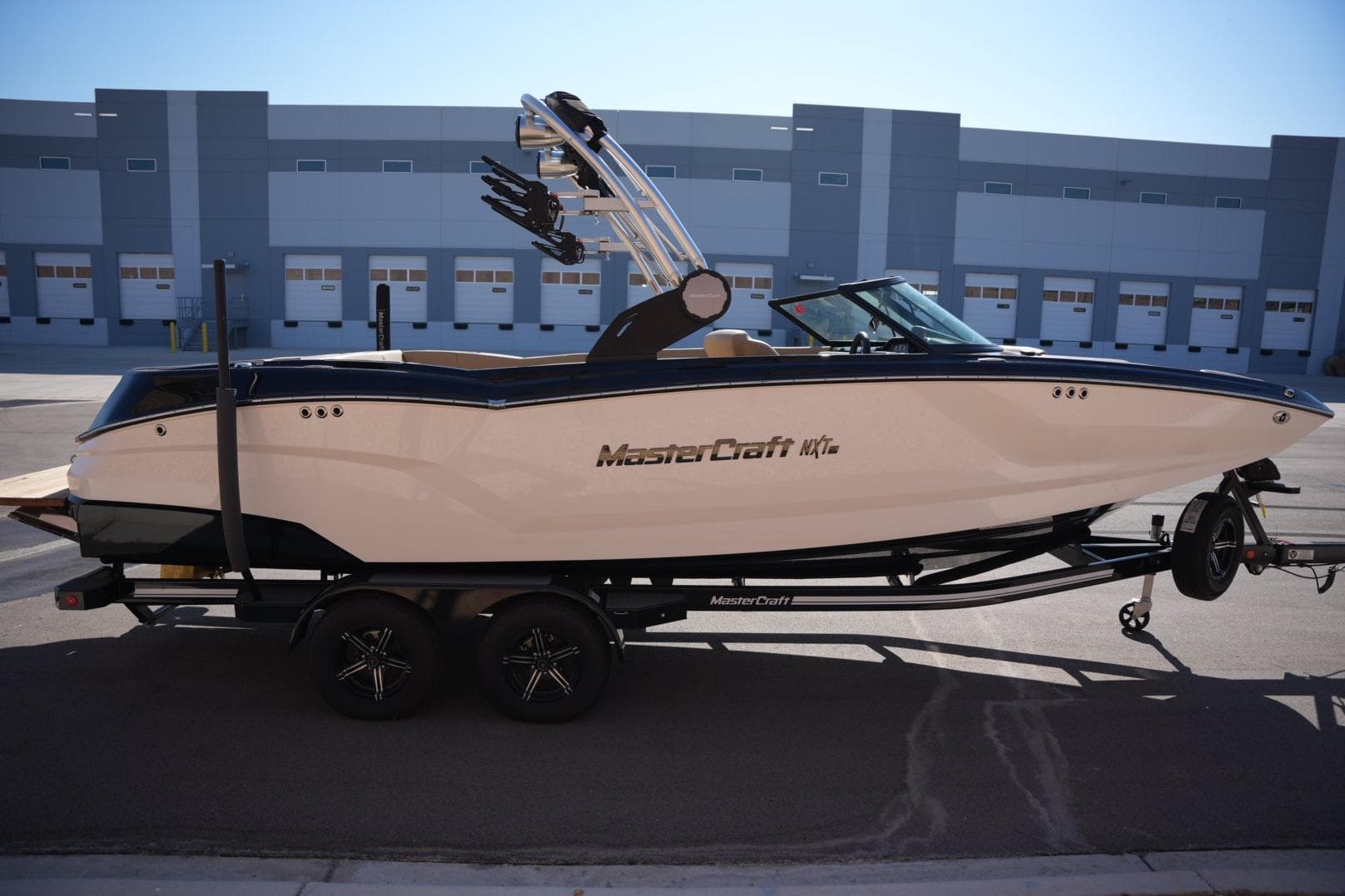 2023 MasterCraft NXT24 boat on trailer, parked in industrial area.