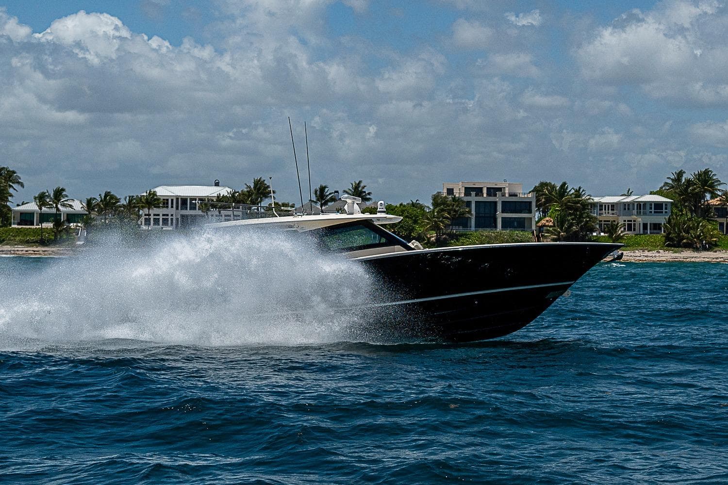 2025 Scout 425 LXF boat cruising on ocean near luxury waterfront homes.