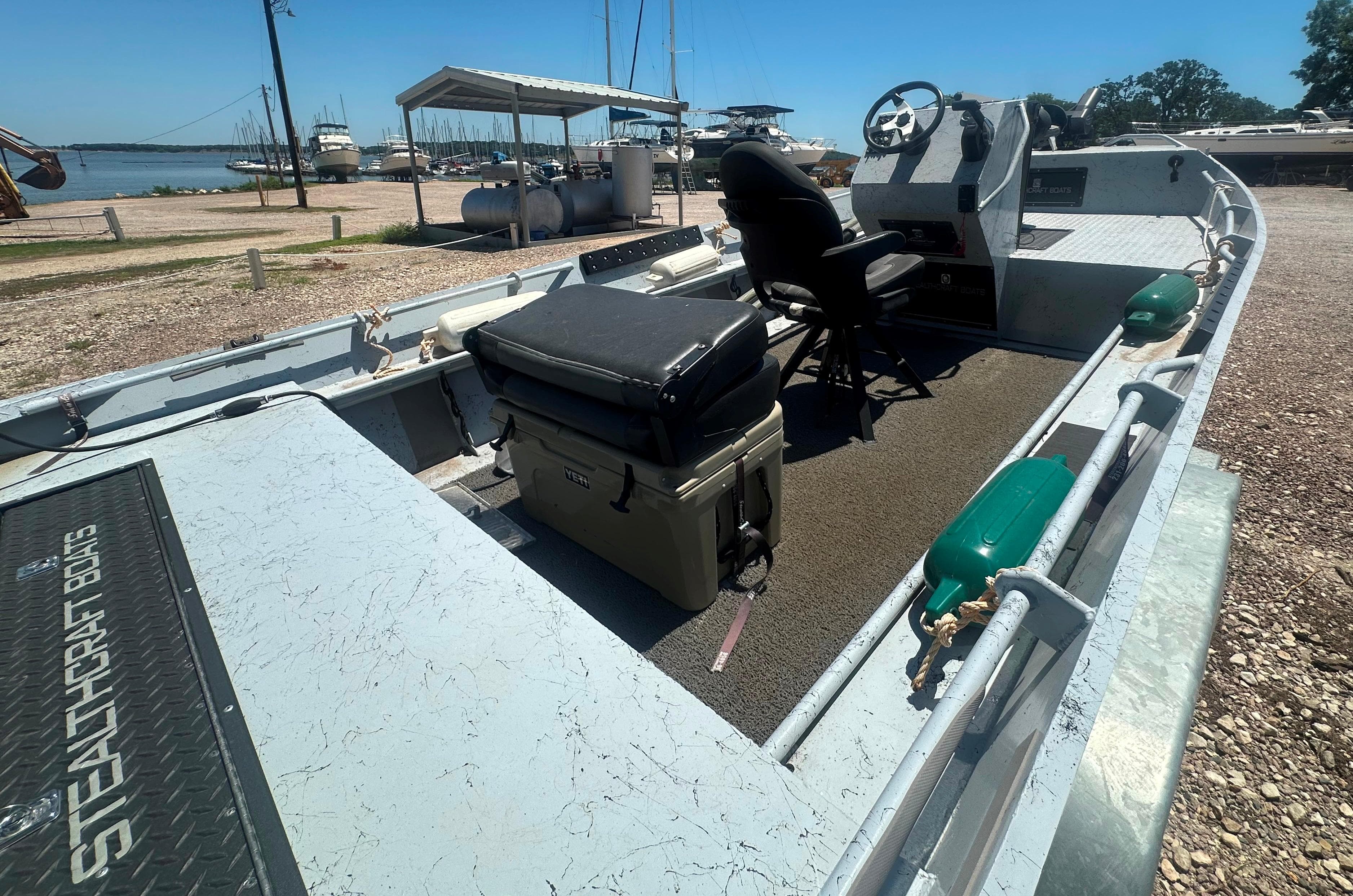 2023 StealthCraft Stealthweld 18 boat with seating and steering, docked near a marina.