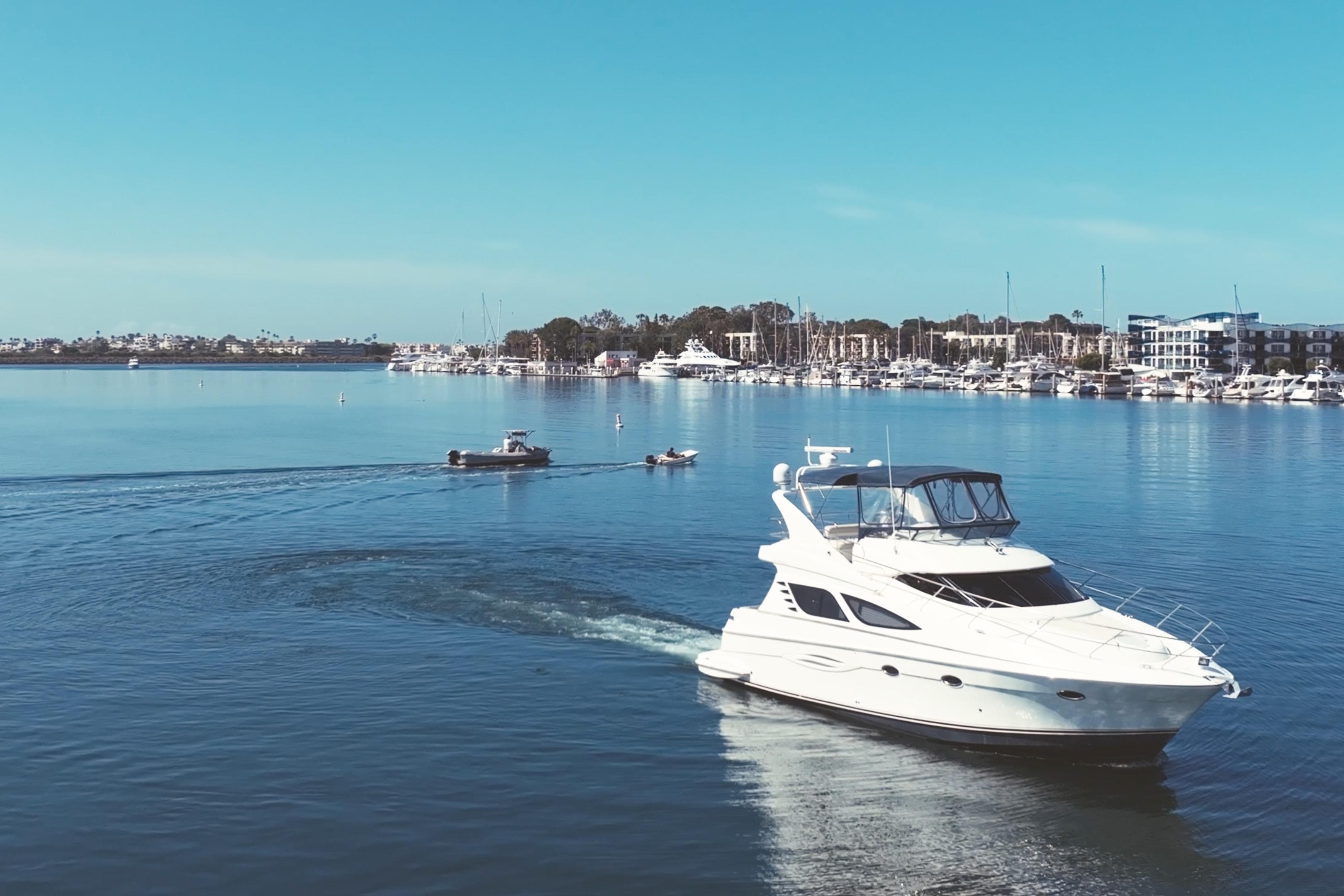 2008 Silverton 43 Sport Bridge yacht cruising in a serene marina with clear blue skies.