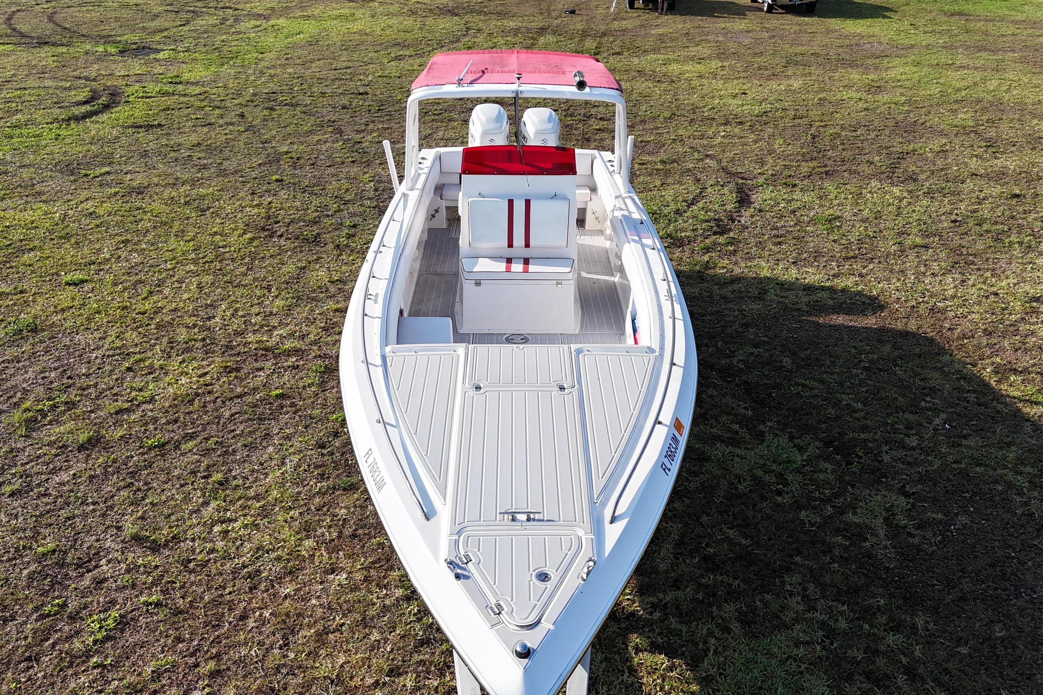 1992 Baja 280 Sportfish boat with red canopy on grassy terrain.