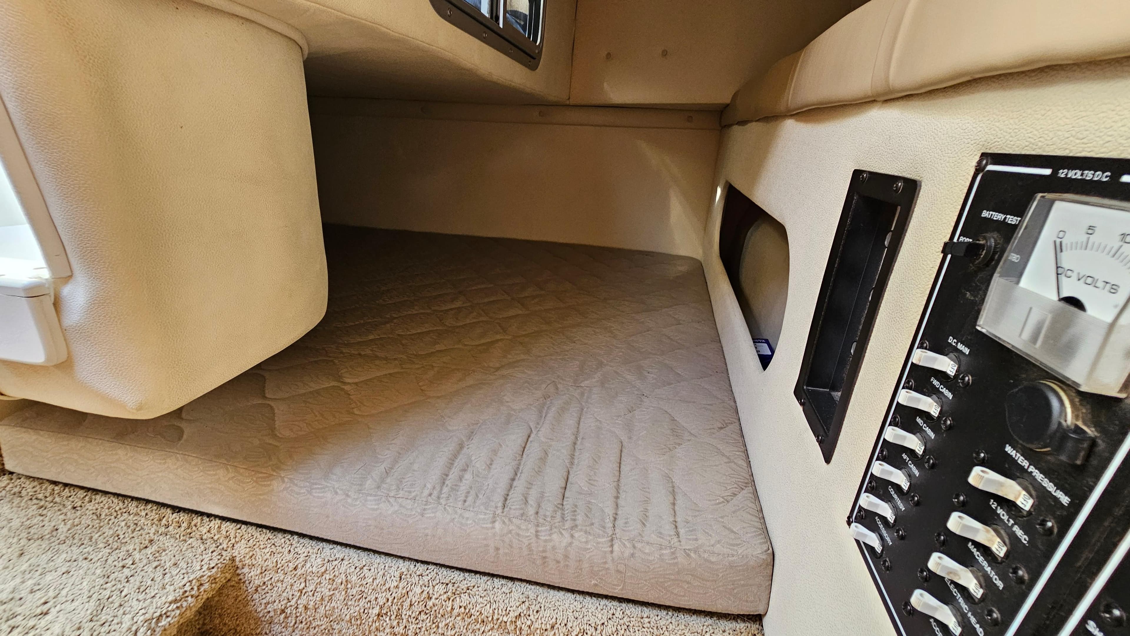 Interior cabin of 2006 Larson 274 Cabrio boat with control panel and cushioned sleeping area.