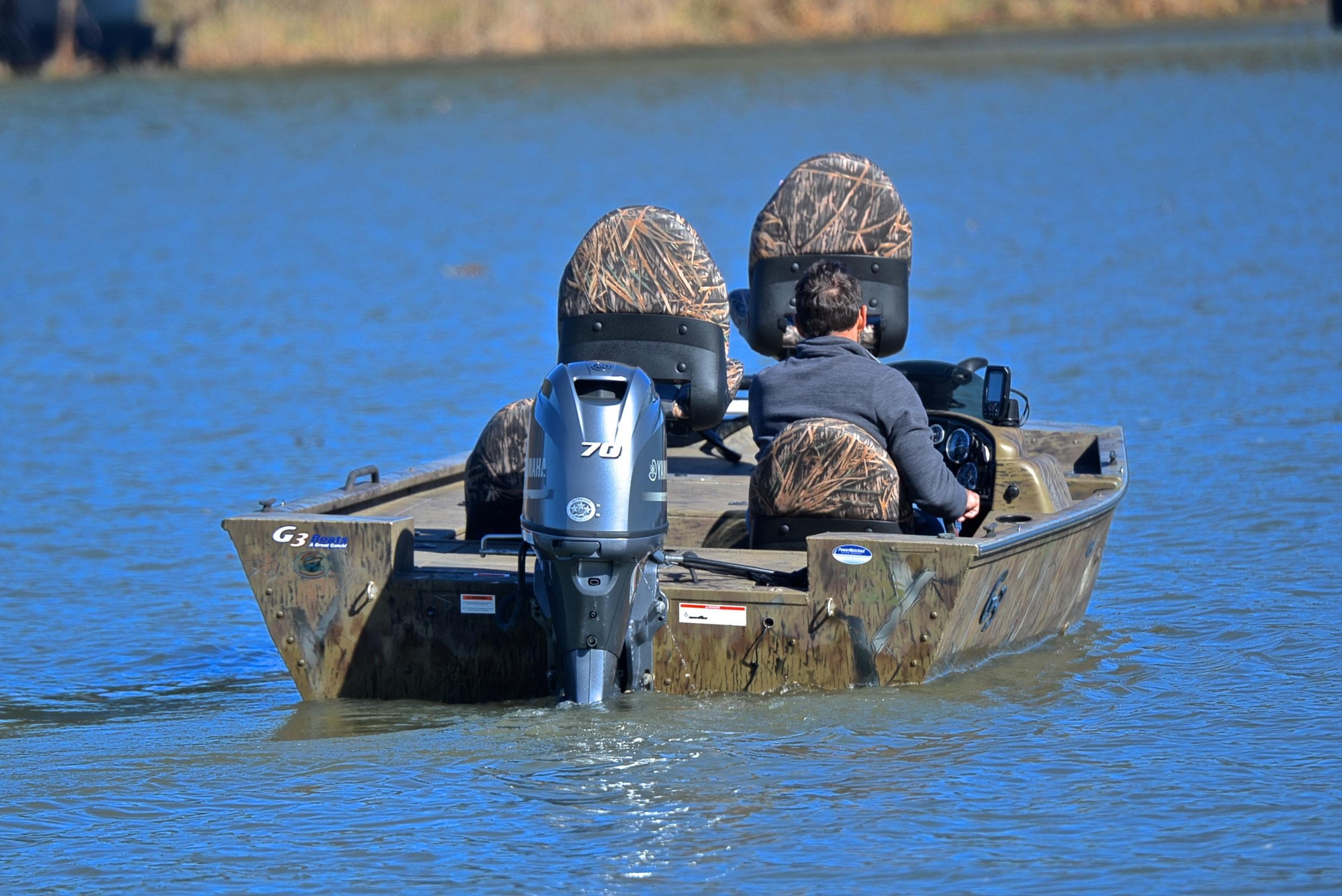2016 G3 Eagle 176 boat on a lake with camo seats and outboard motor.