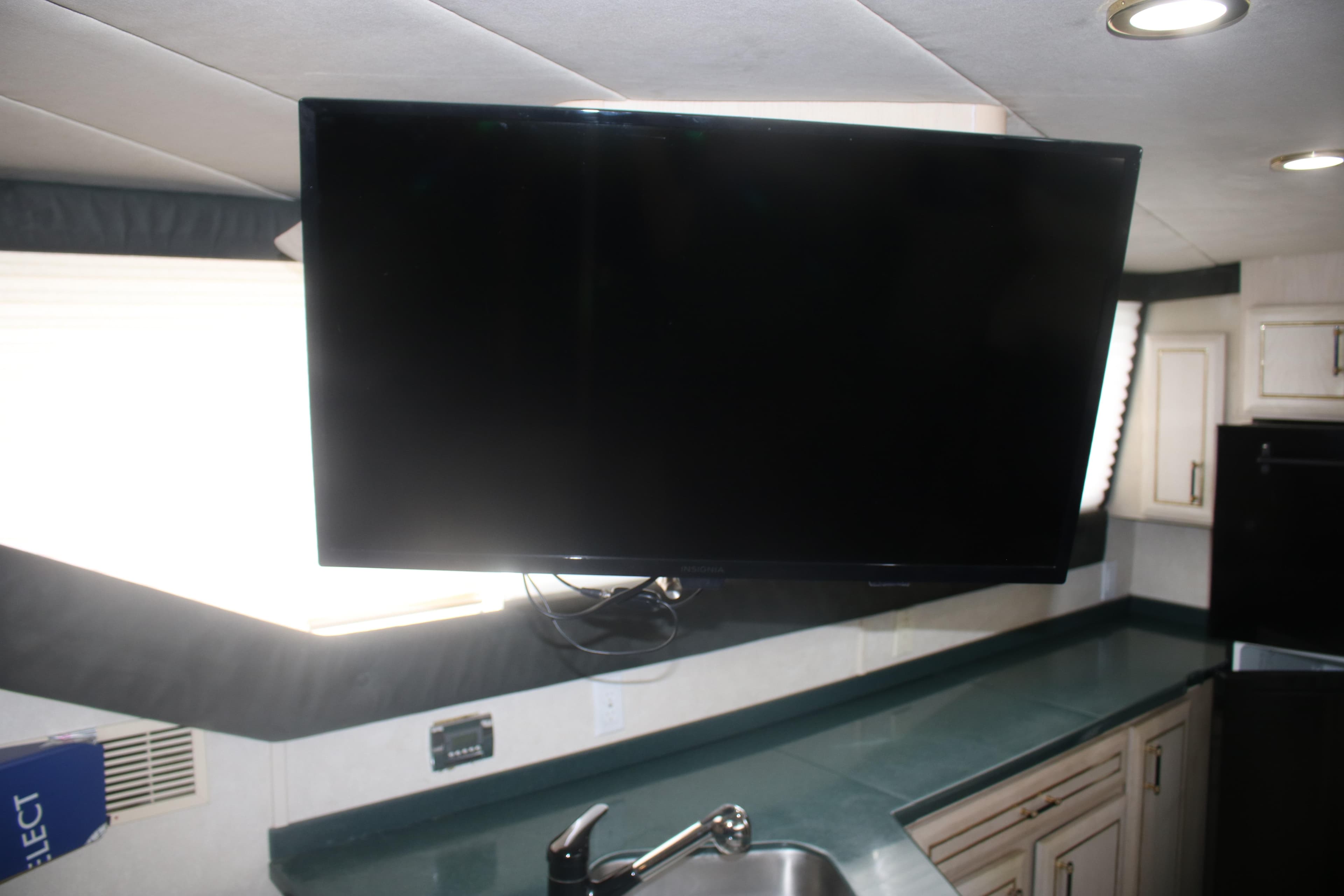 Interior of 1998 Mainship 47 Motor Yacht with mounted TV and kitchen sink.