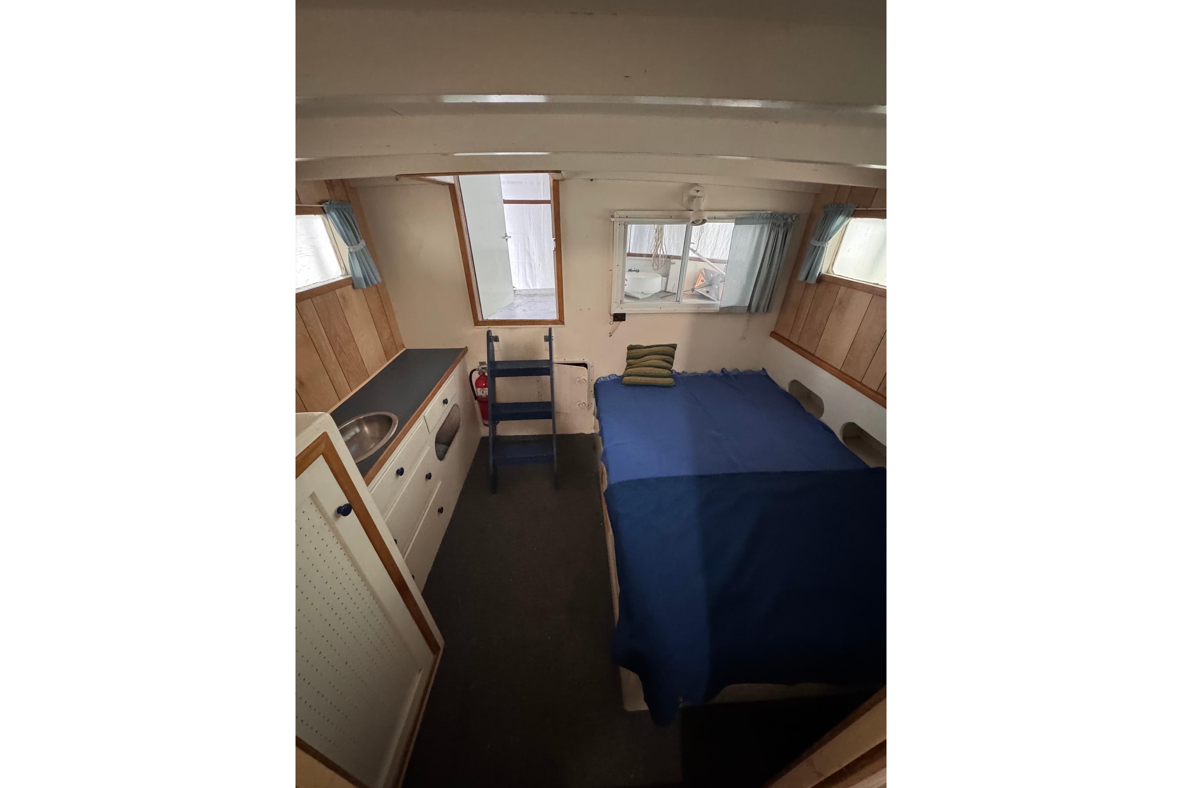 Cozy cabin interior of 2000 Custom Yukon 42 Trawler with bed and kitchenette.