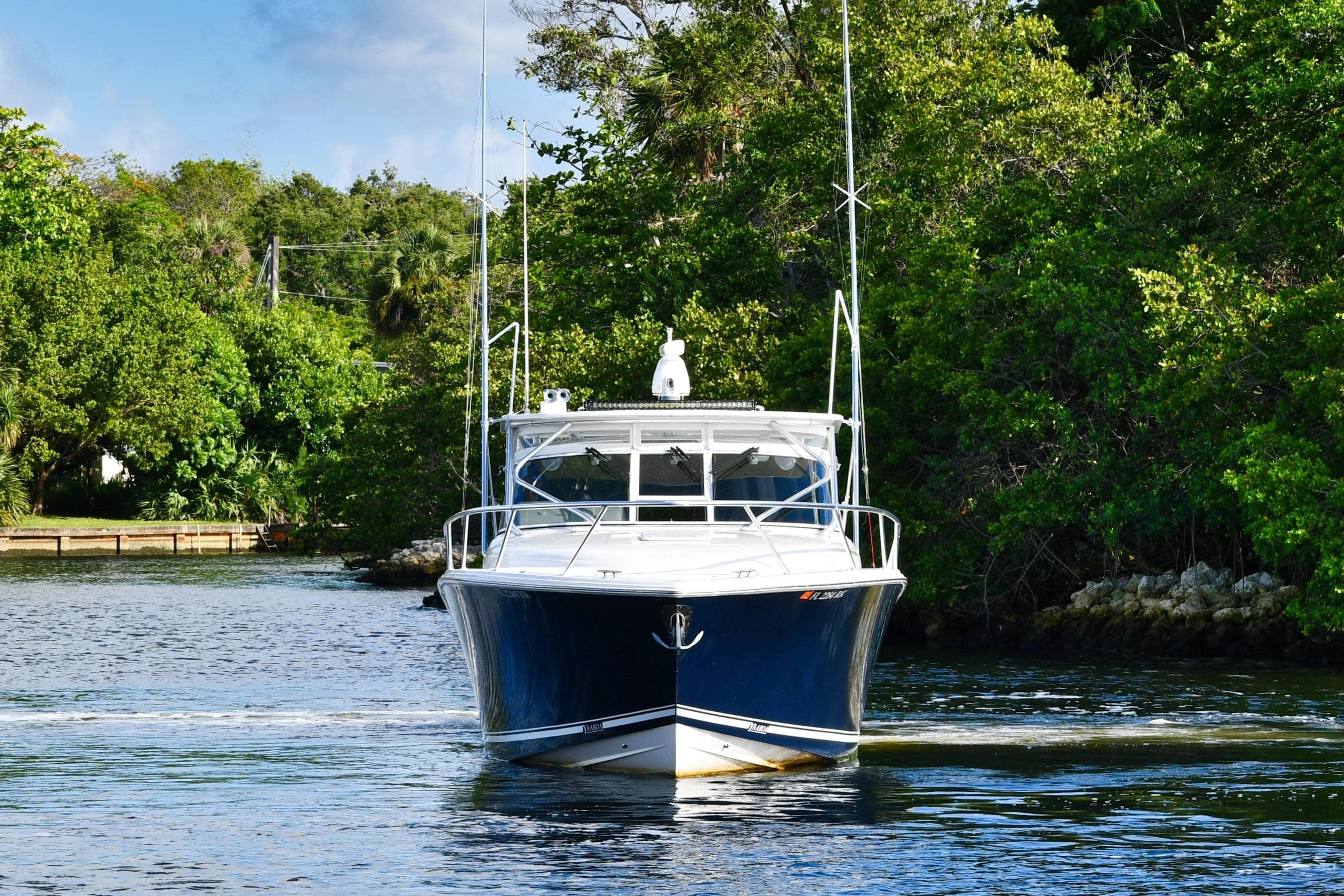 2009 Jupiter 39 Express boat cruising on a scenic waterway surrounded by lush greenery.
