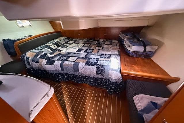 Cozy cabin interior of 2005 Hunter 38 sailboat with quilted bed and wooden accents.