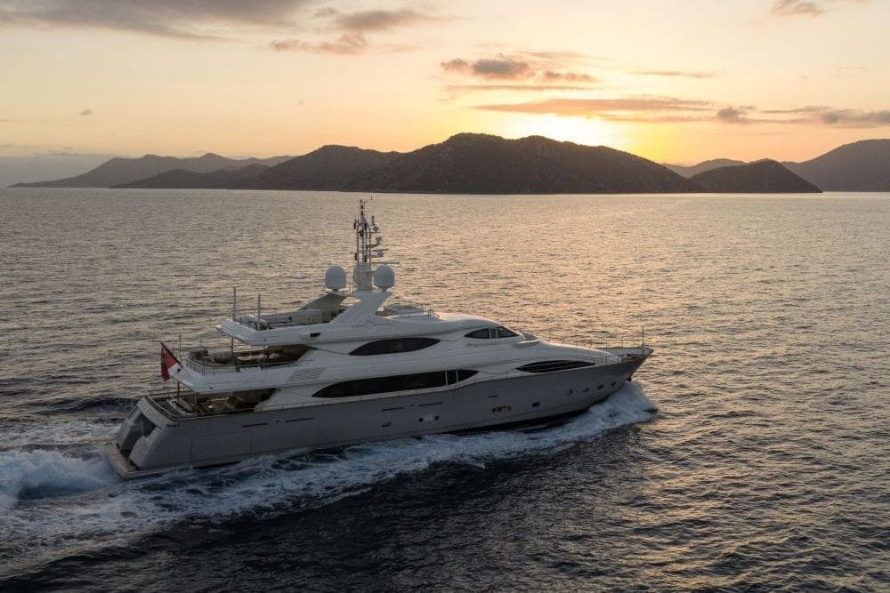 Luxurious CRN 129 yacht cruising at sunset near scenic islands, 2009 model.