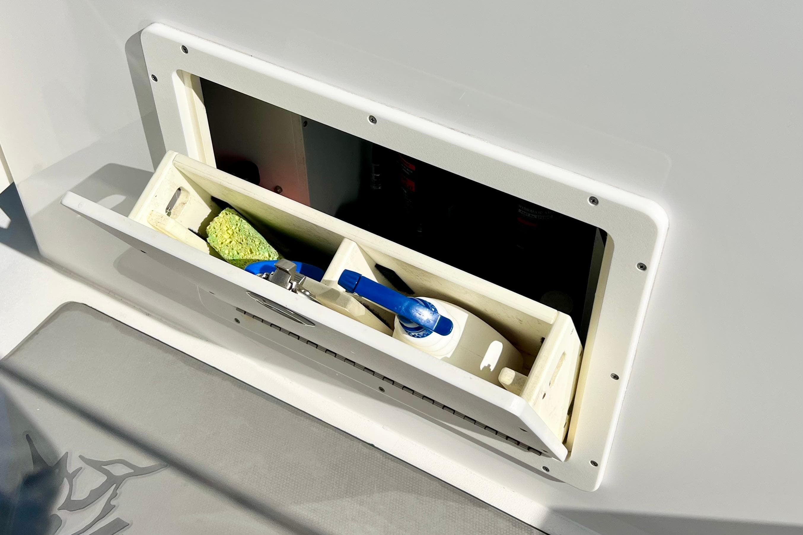 Open storage compartment on a 2015 Freeman 34VH boat with cleaning supplies.