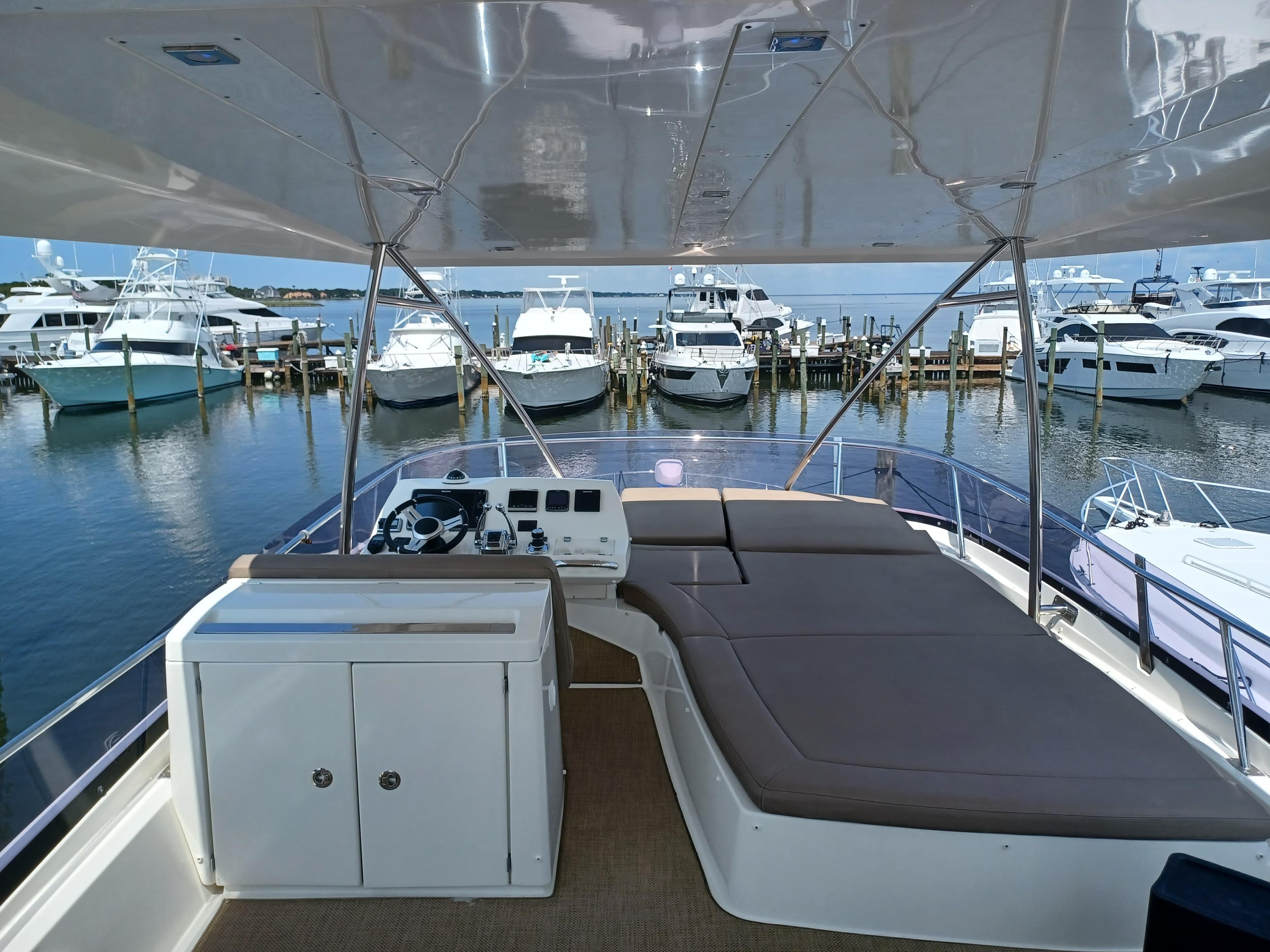 Flybridge view of 2015 Prestige 550 yacht docked at marina with multiple boats.
