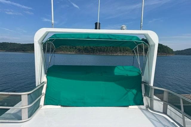 1992 Lakeview Houseboat with green canopy on a serene lake.