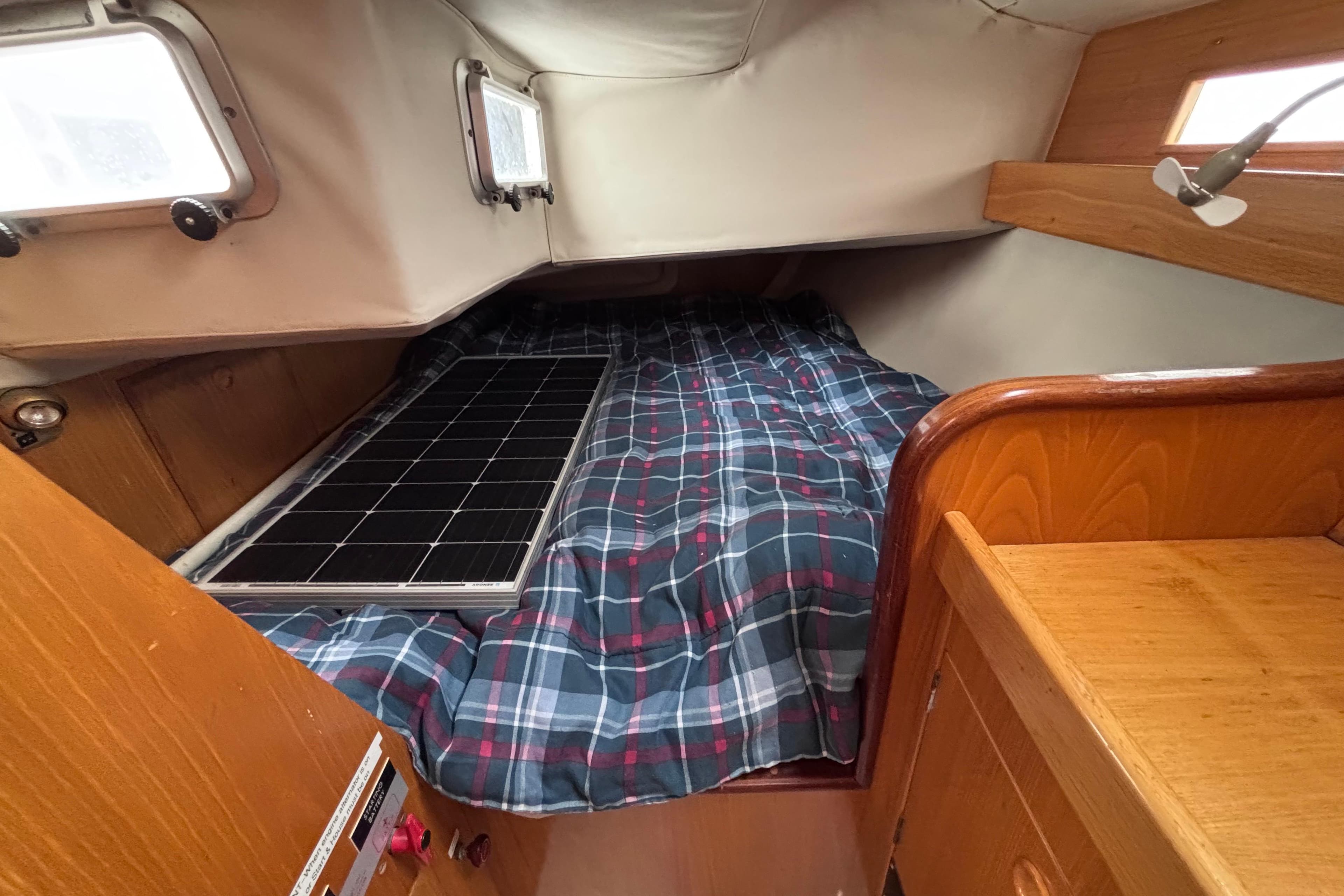 Cozy cabin interior of 1990 Beneteau Oceanis 350 sailboat with plaid bedding.