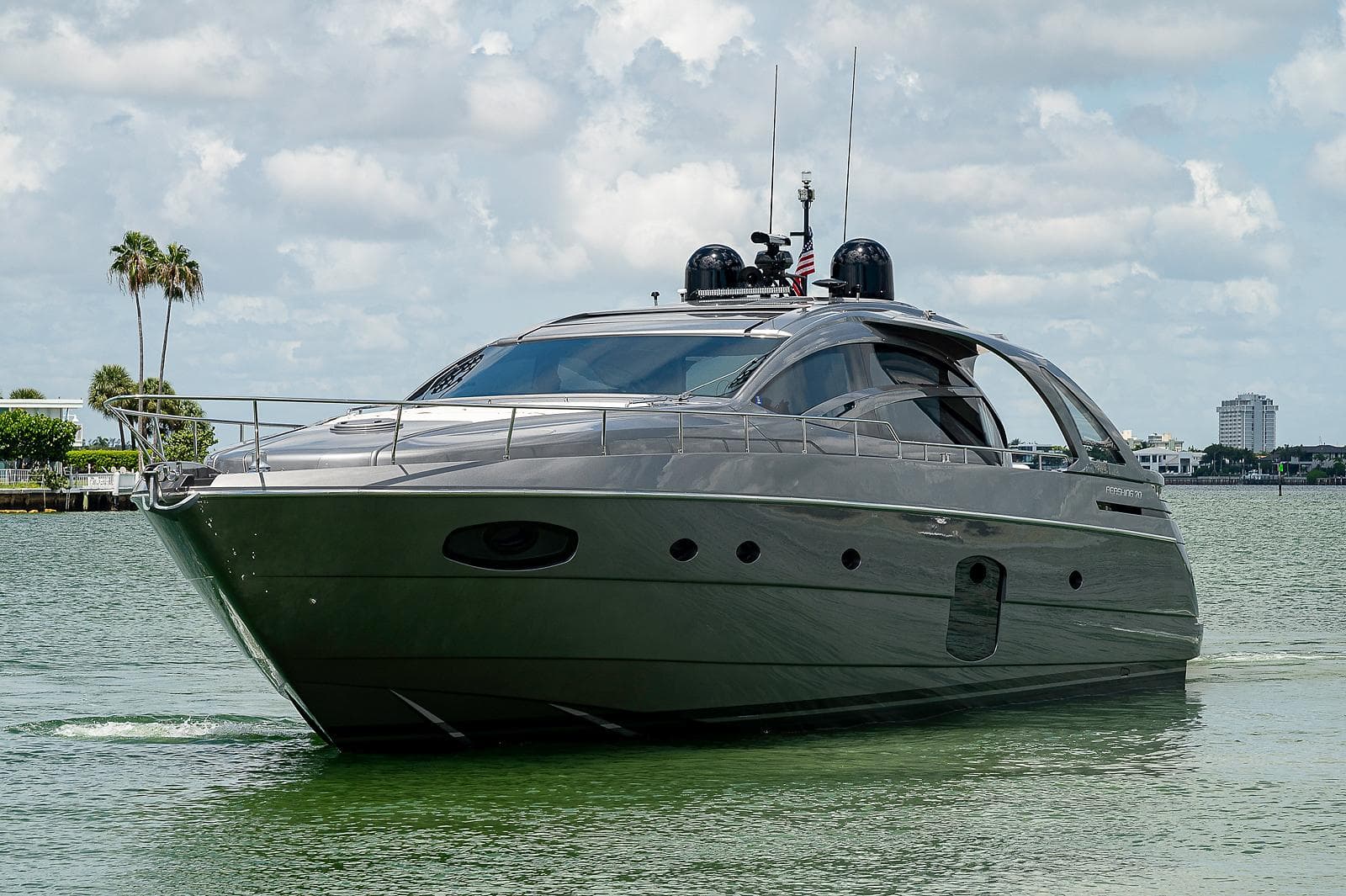 2015 Pershing 70 yacht cruising on a calm, scenic waterway under a partly cloudy sky.