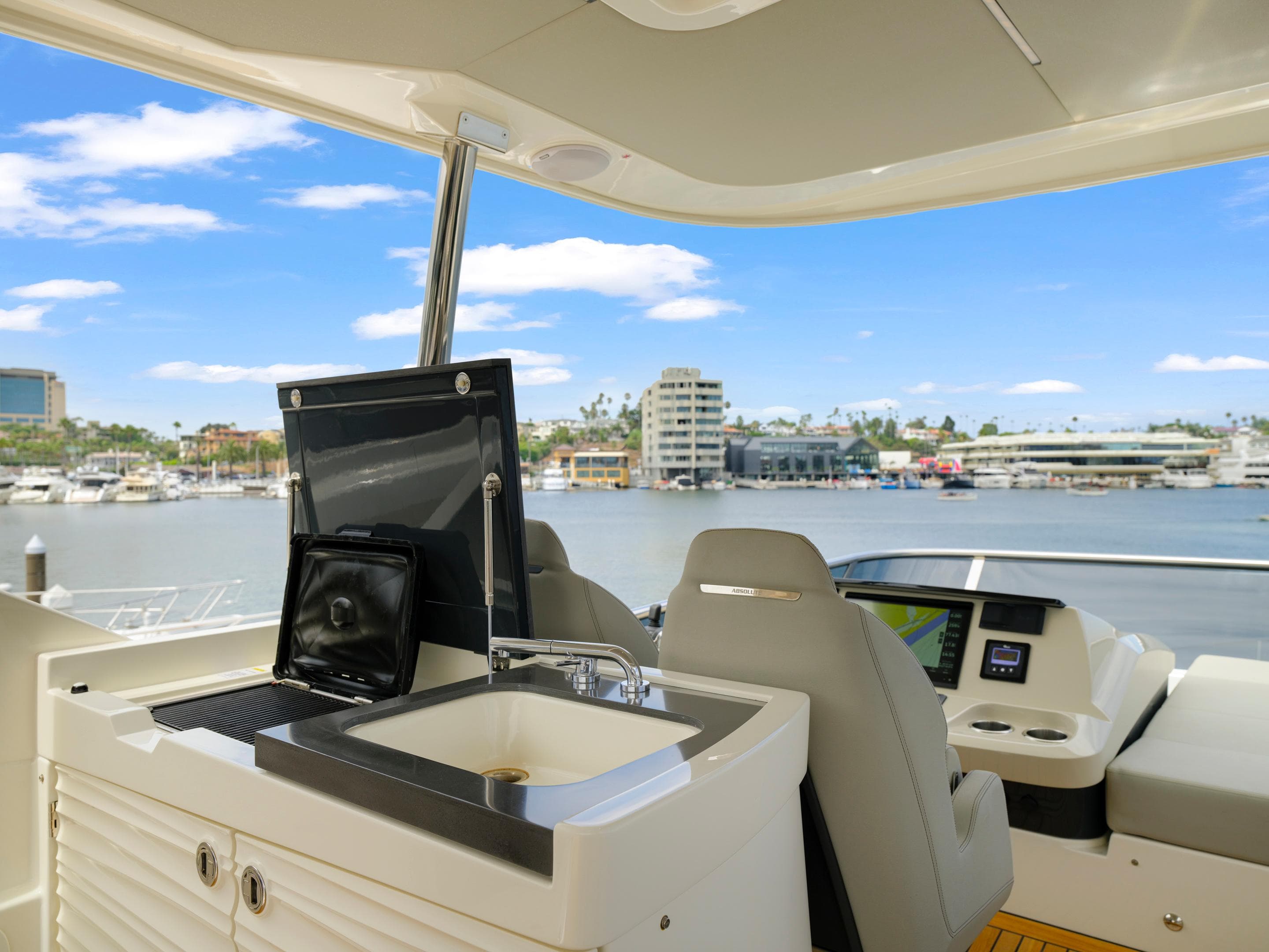 Flybridge of 2024 Absolute 60 Fly yacht with sink and seating, overlooking marina.