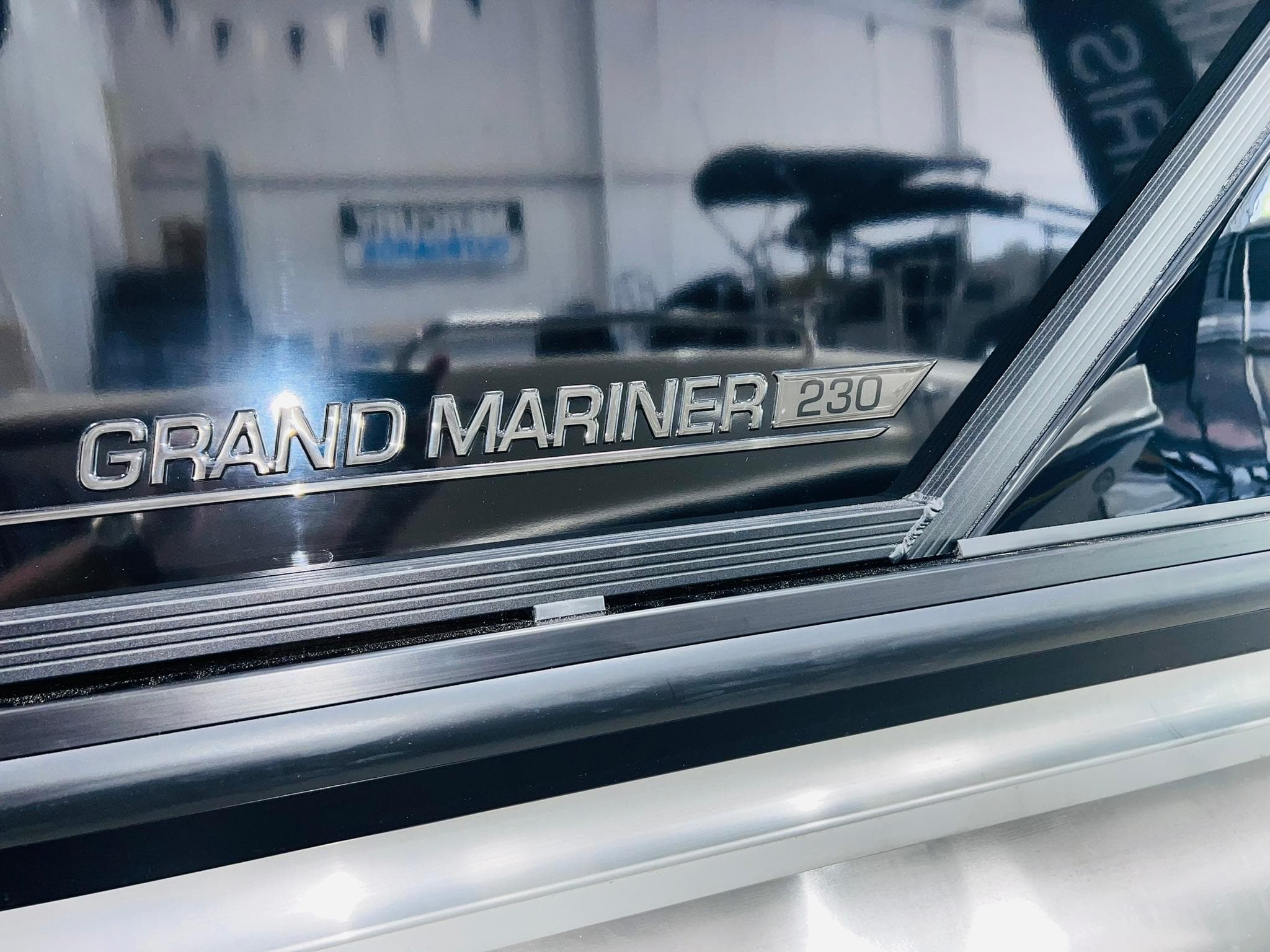 Close-up of 2025 Harris Grand Mariner 230 logo on a sleek boat surface.