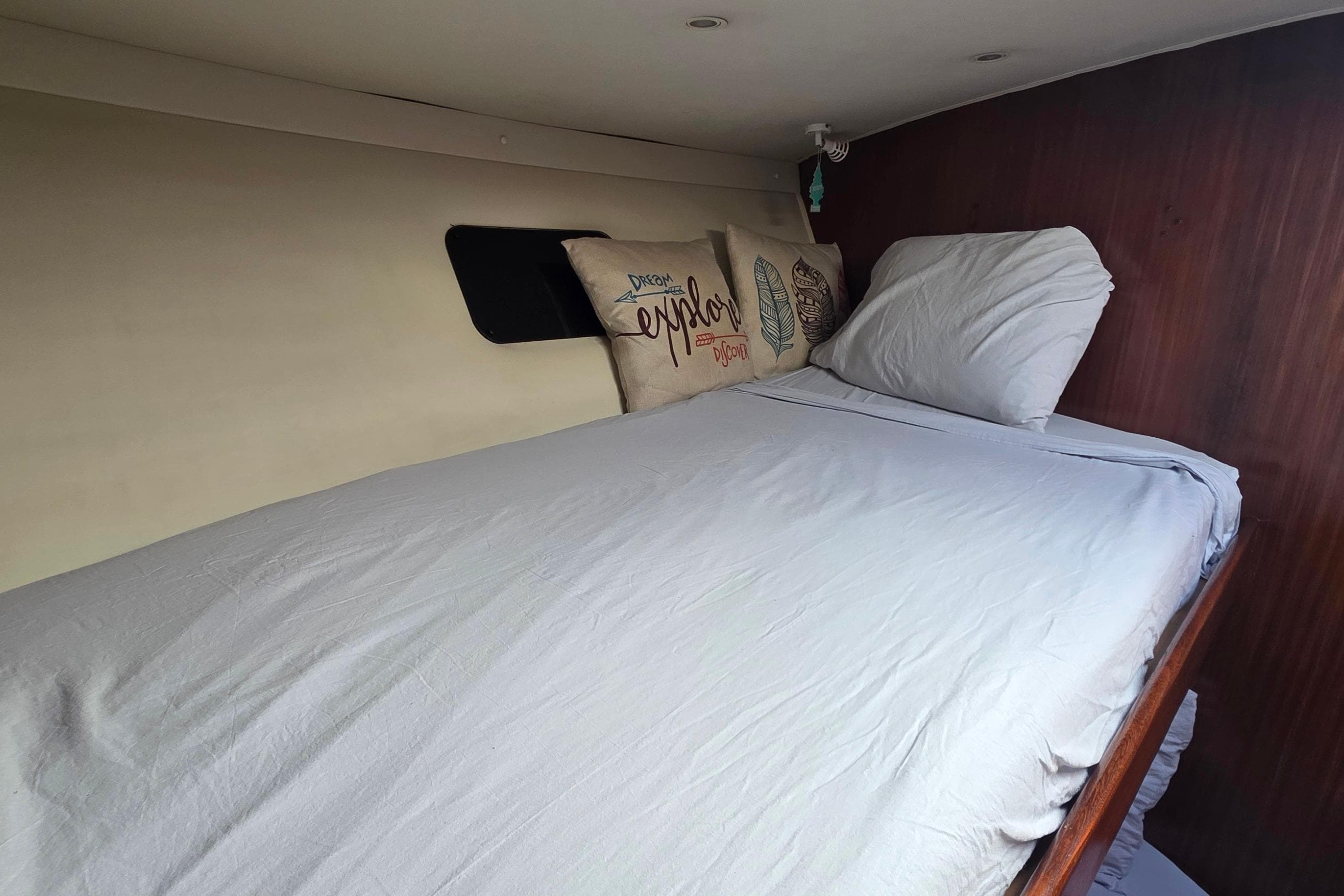 Cozy cabin bed inside 1989 Hatteras 52 Convertible yacht with decorative pillows.