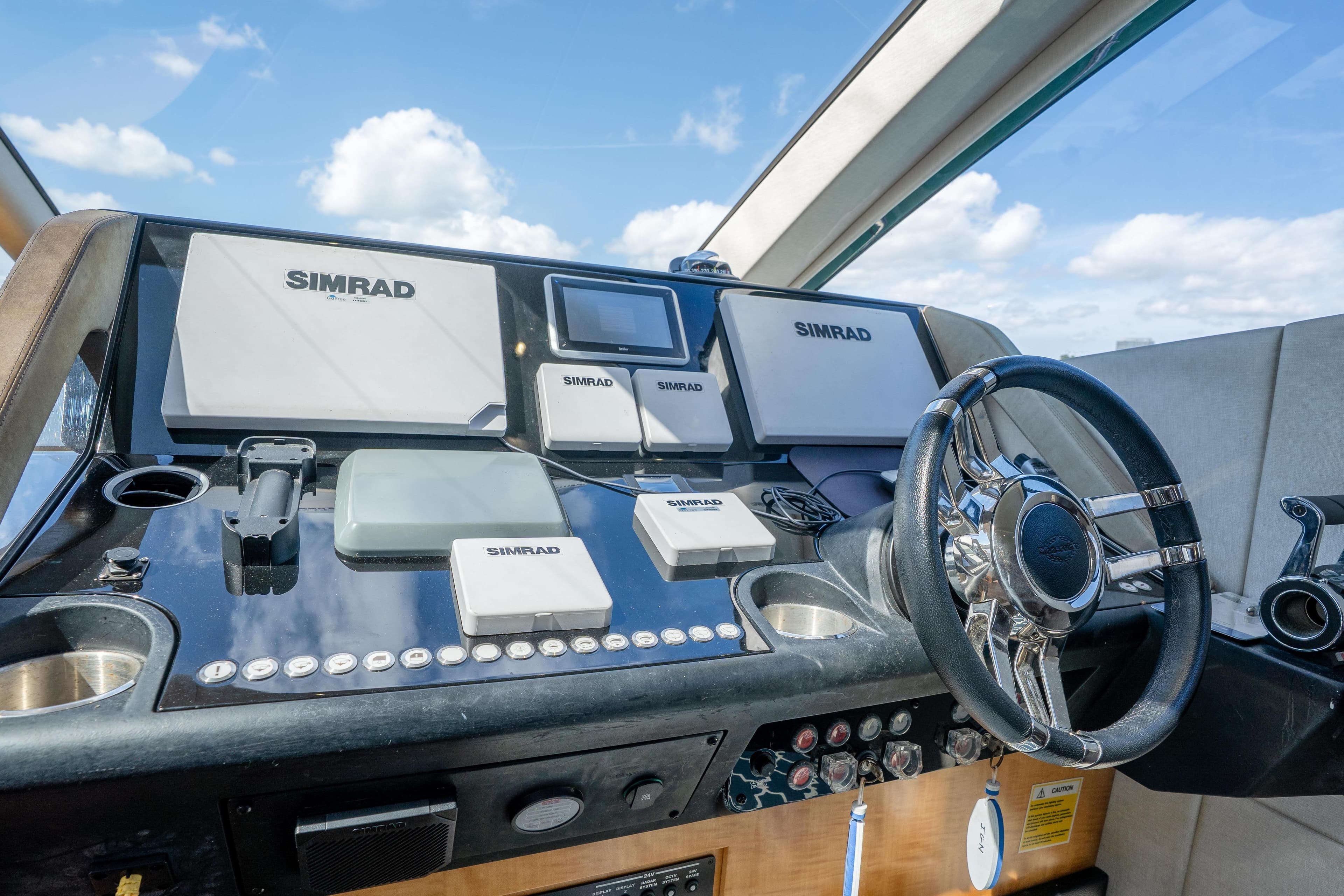 Helm of 2014 Sunseeker 68 Sport Yacht with Simrad navigation systems and sleek steering wheel.