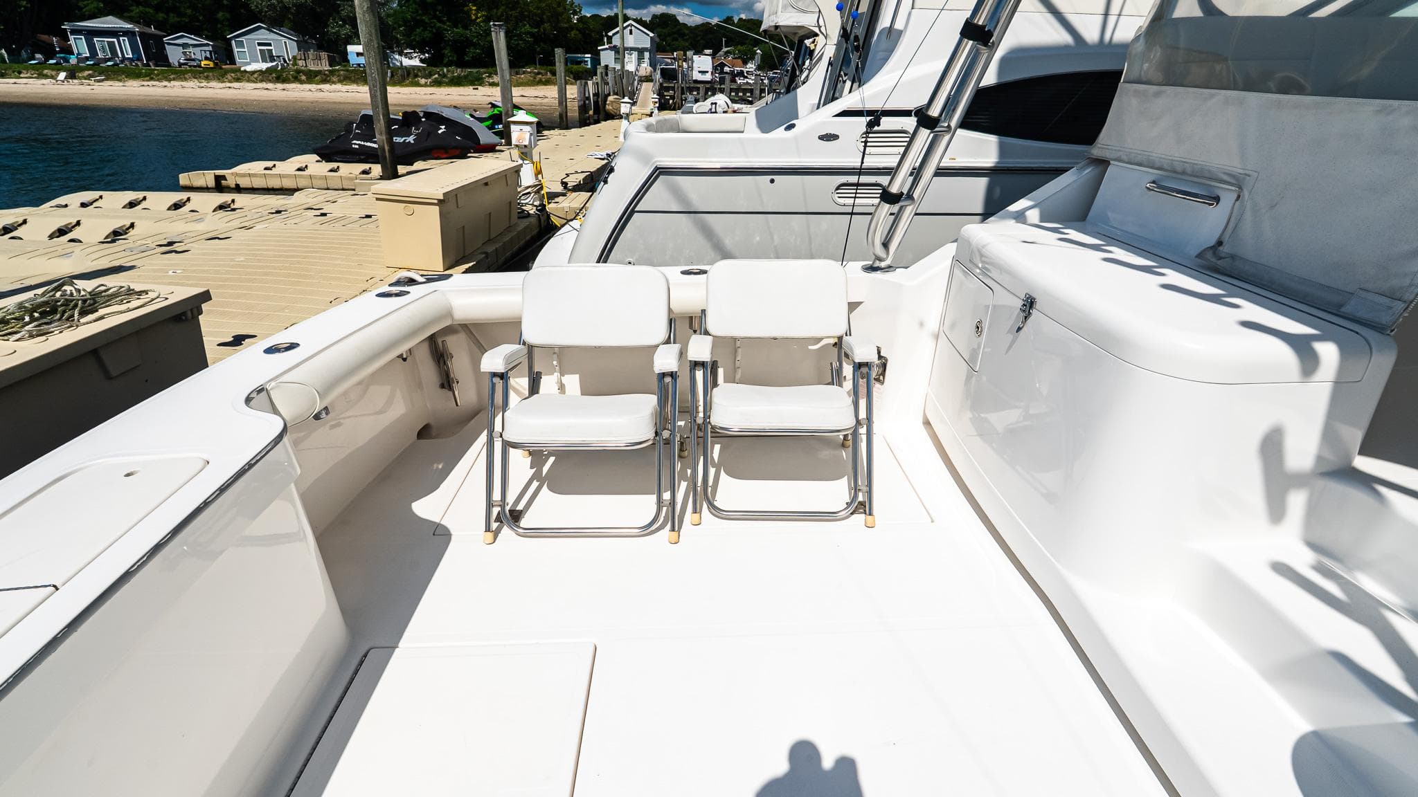 2008 Cabo 38 Express boat deck with chairs, docked by the water.