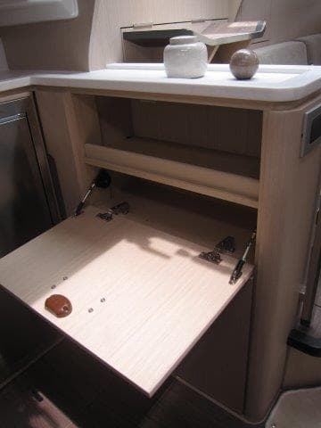2024 Jeanneau 55 yacht interior, showcasing a fold-down wooden cabinet.
