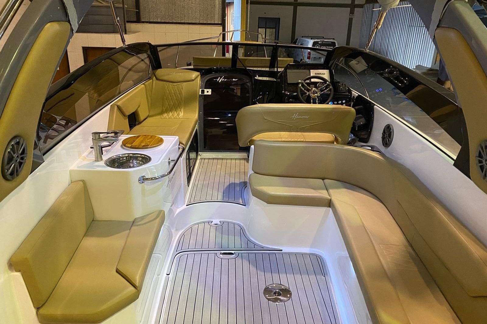 Luxurious interior of 2024 Hanover 305 boat with beige seating and modern amenities.