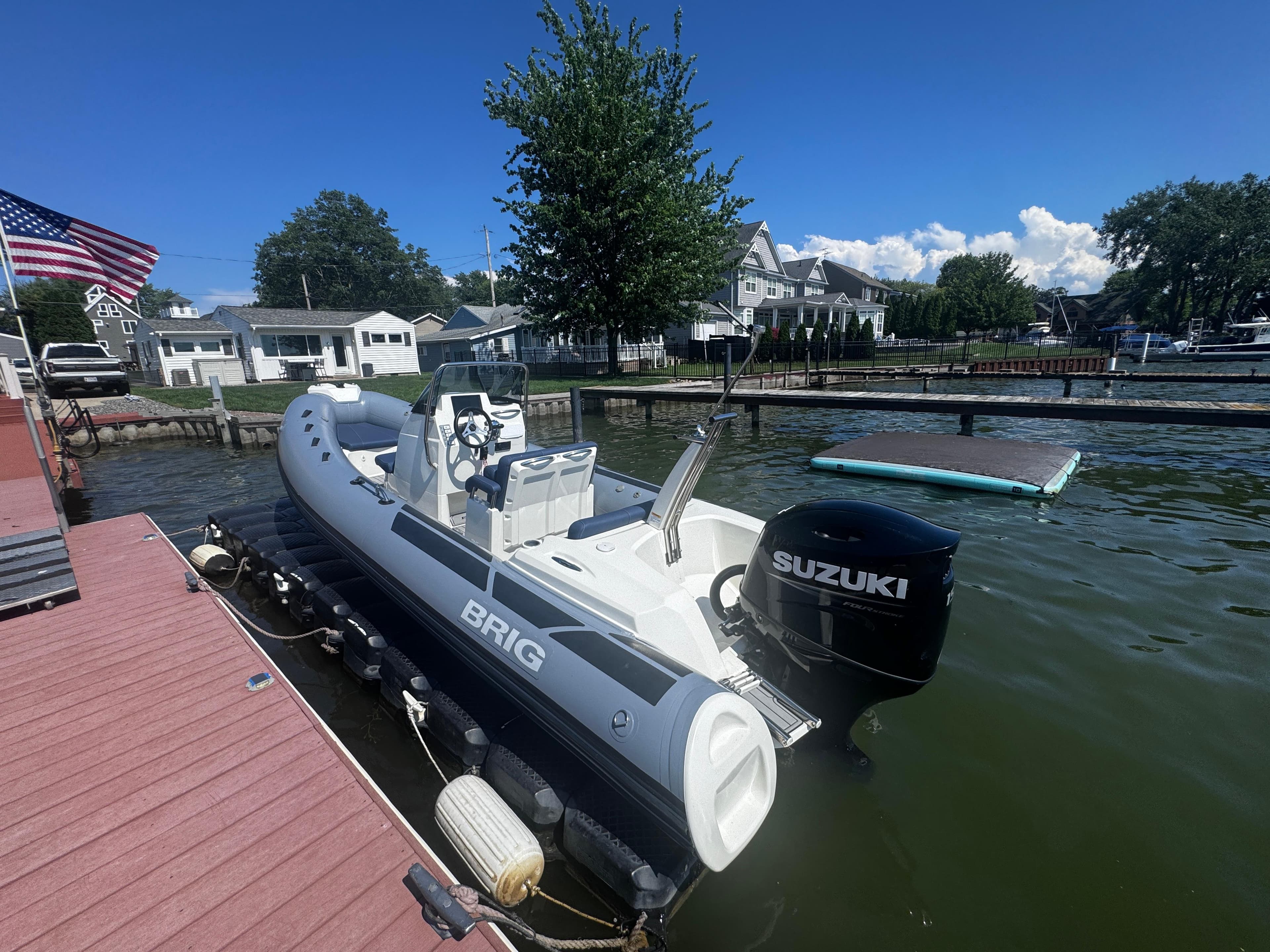 2022 Brig Eagle 6 boat docked with Suzuki outboard motor, American flag nearby.