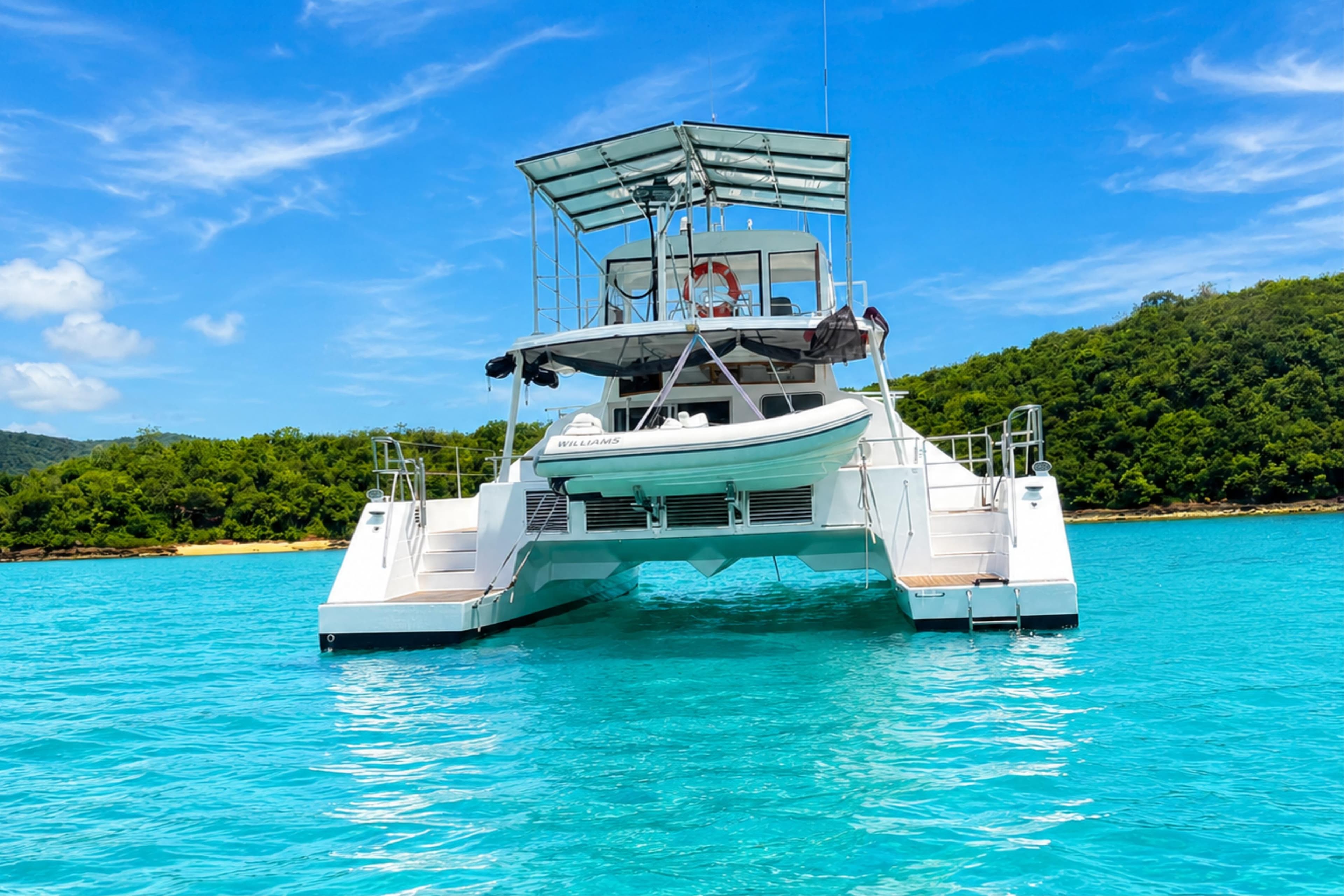 2007 Sun Yachts Custom 56 Power Cat on turquoise waters, lush island backdrop.